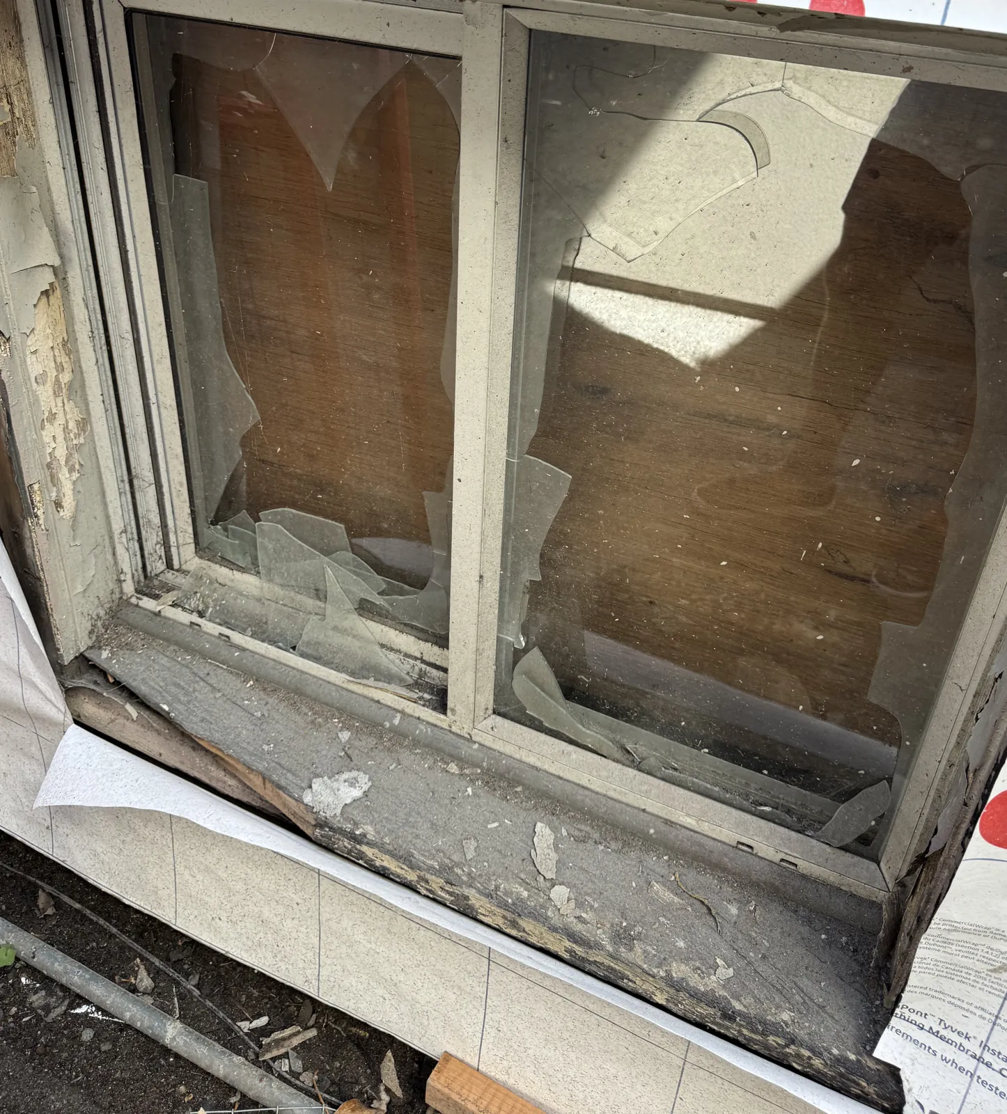 A broken original window with a peeling, lead-painted sill