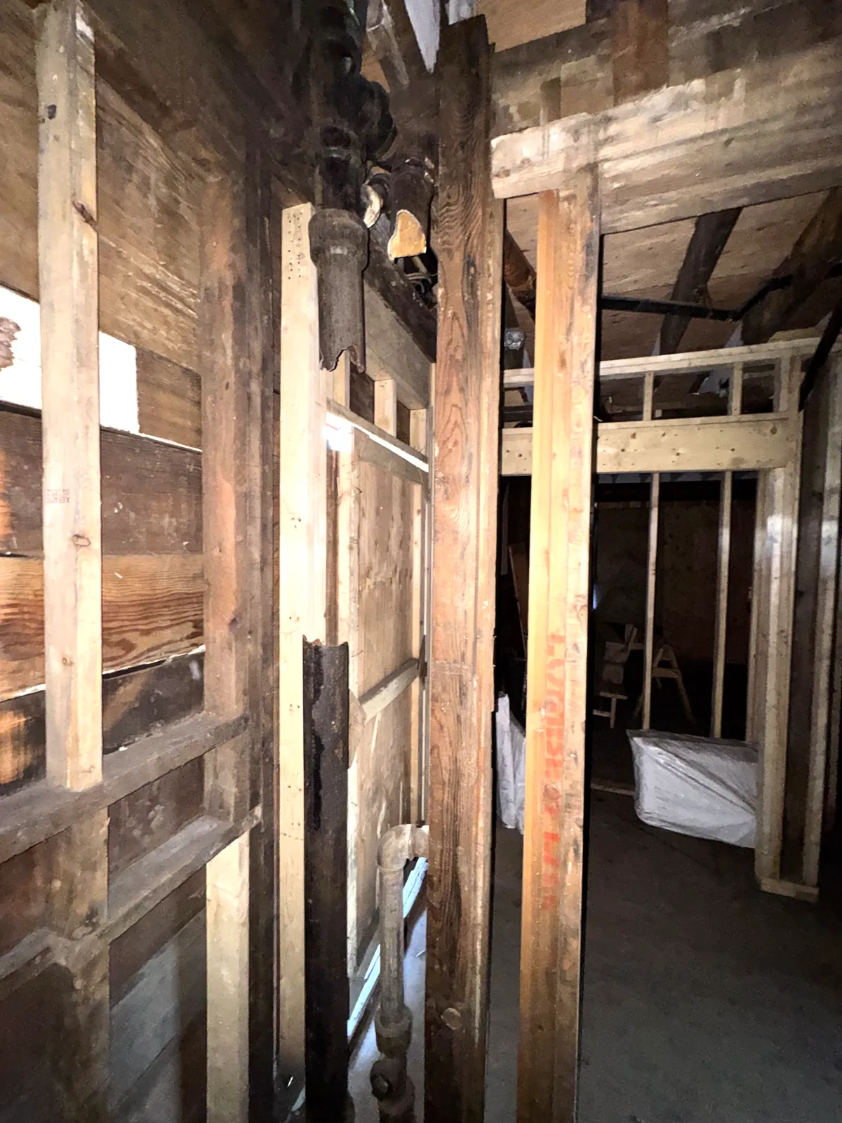Deep charring on retained framing, with the old cast iron stack still in the wall
