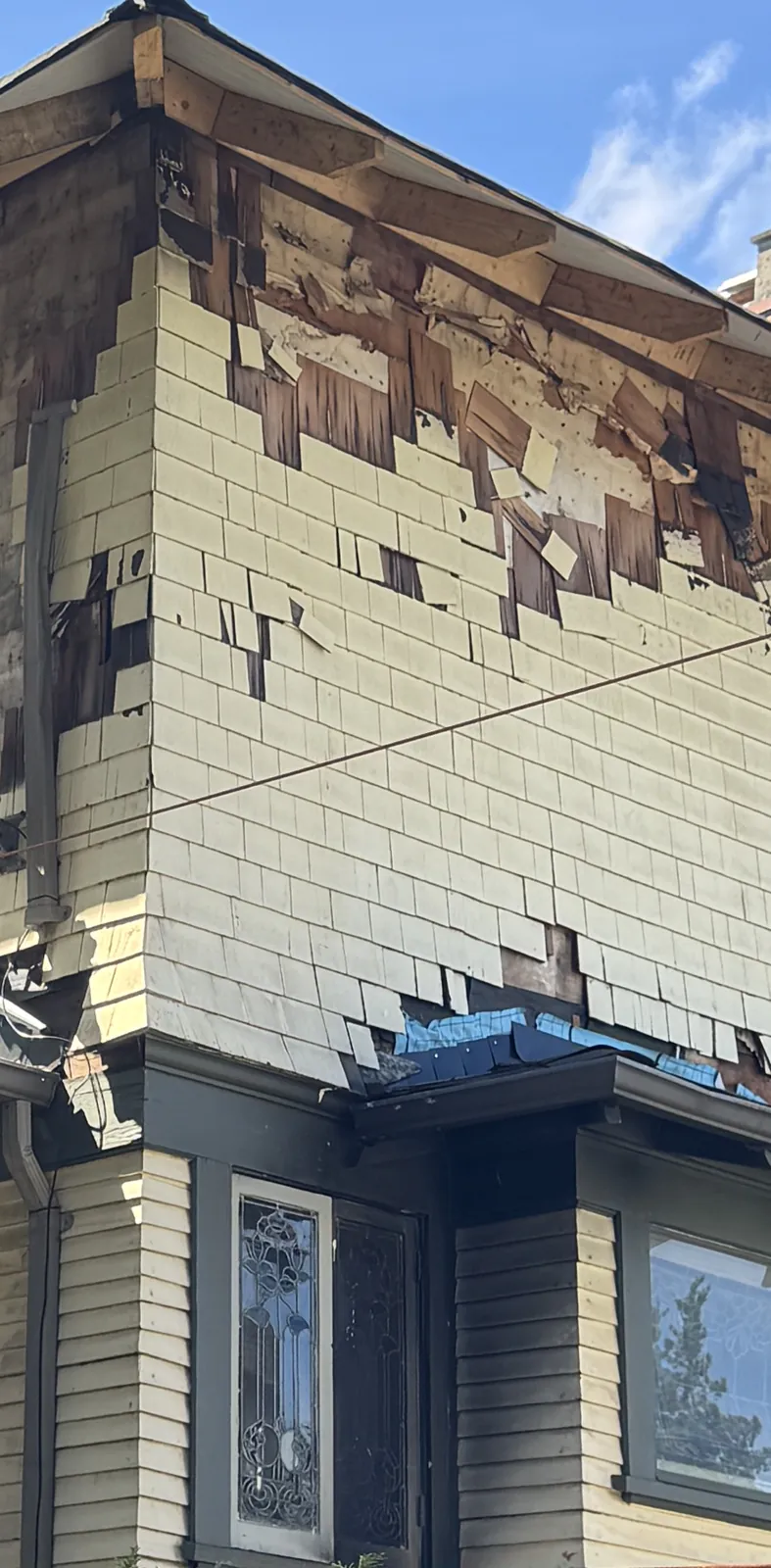 Fire-damaged cedar shingles on the upper storey of a heritage Craftsman, original siding below
