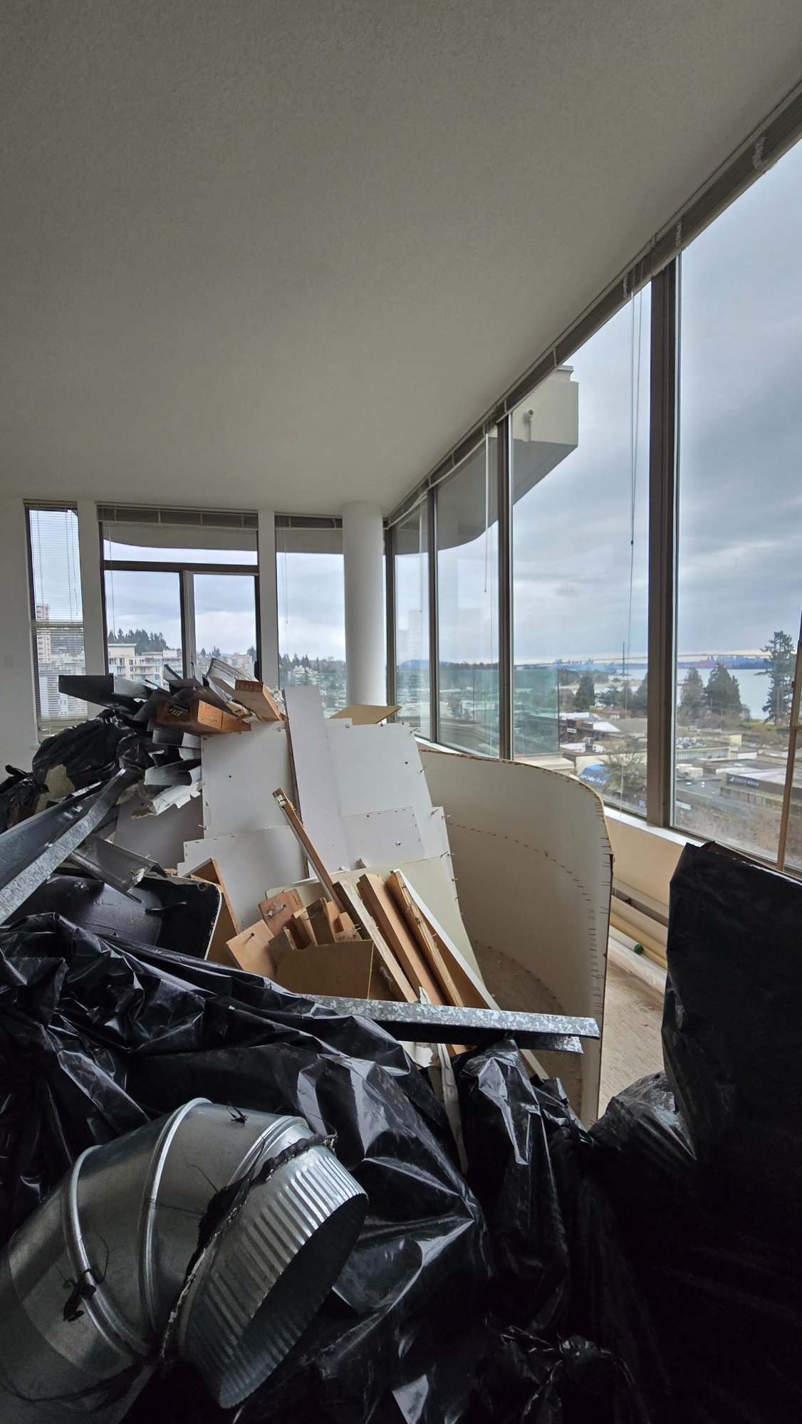 Condo living room during demolition — construction debris with ocean views, West Vancouver