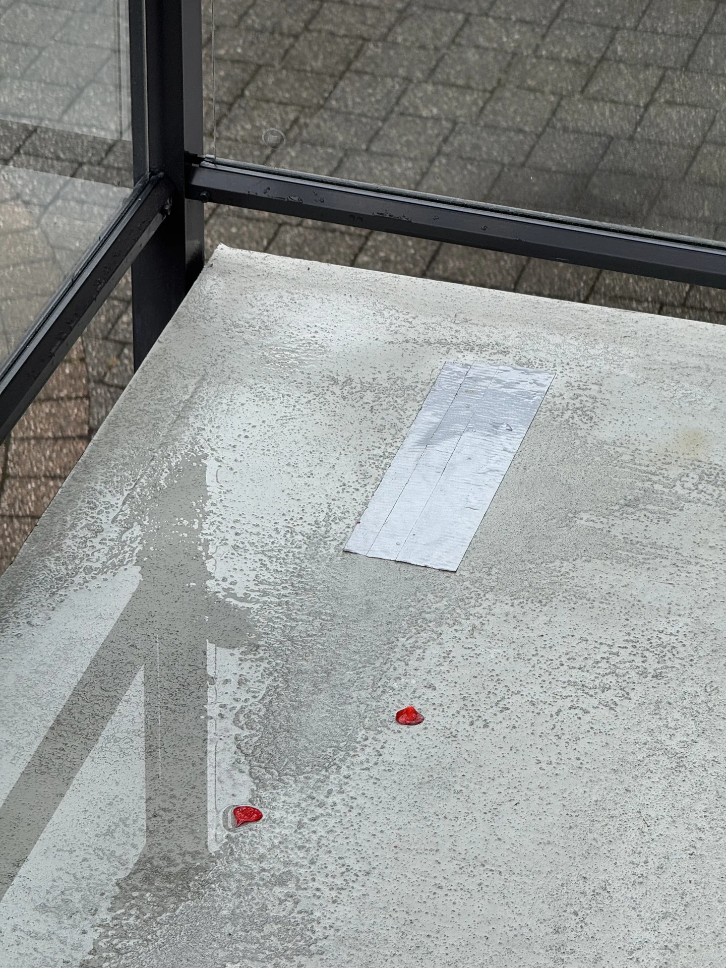 Vinyl balcony deck membrane with a patch repair and glass guardrail on a Greater Vancouver strata balcony