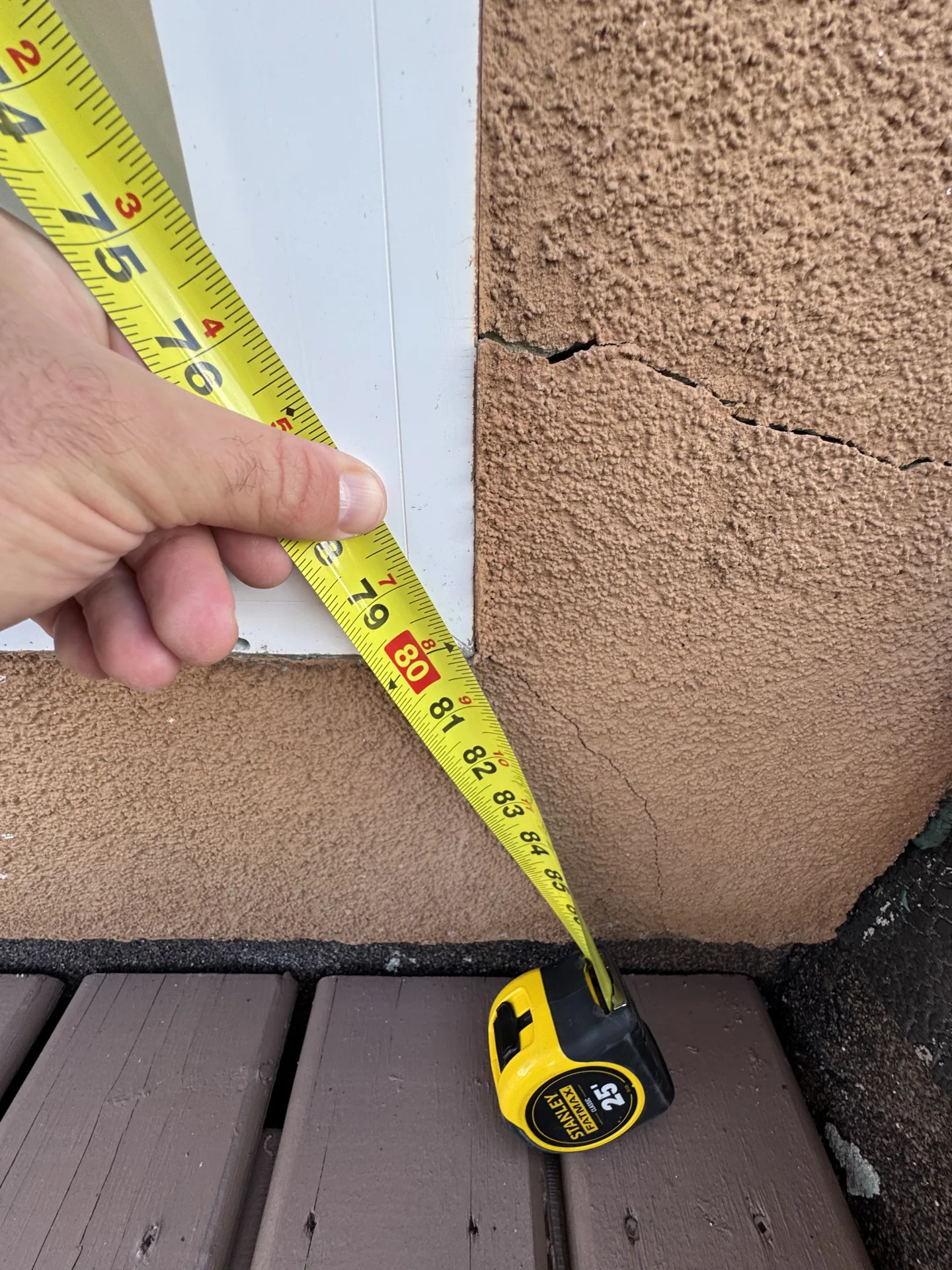Measuring a stucco crack above a deck surface during a balcony membrane and envelope inspection