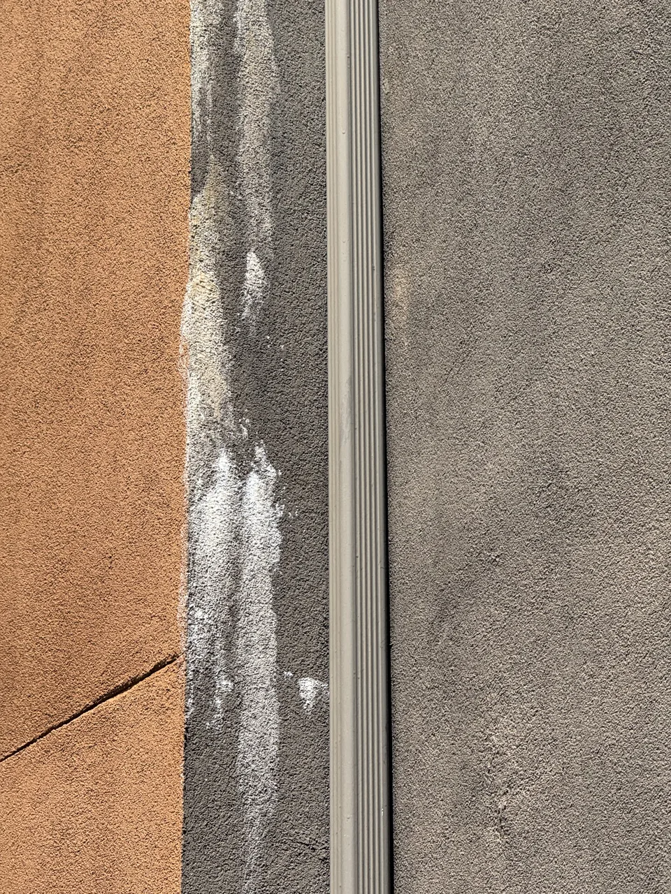 Stucco crack with efflorescence staining on a strata building wall, a visible sign of water getting into the assembly