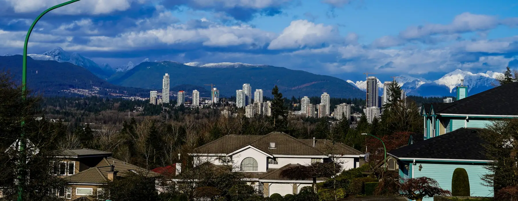 Detached houses on a Vancouver hillside with the city skyline and the North Shore mountains behind