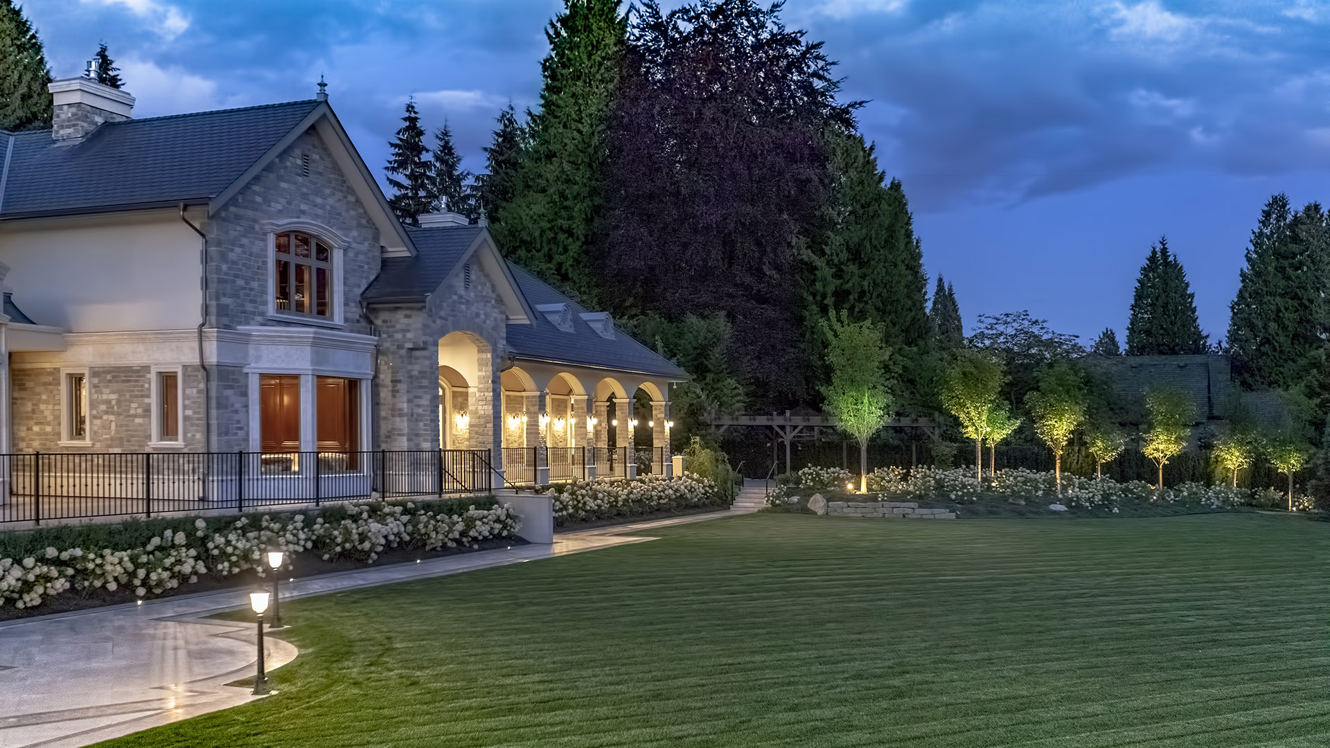 Altamont's Muse rear exterior at dusk with illuminated arched loggia in West Vancouver