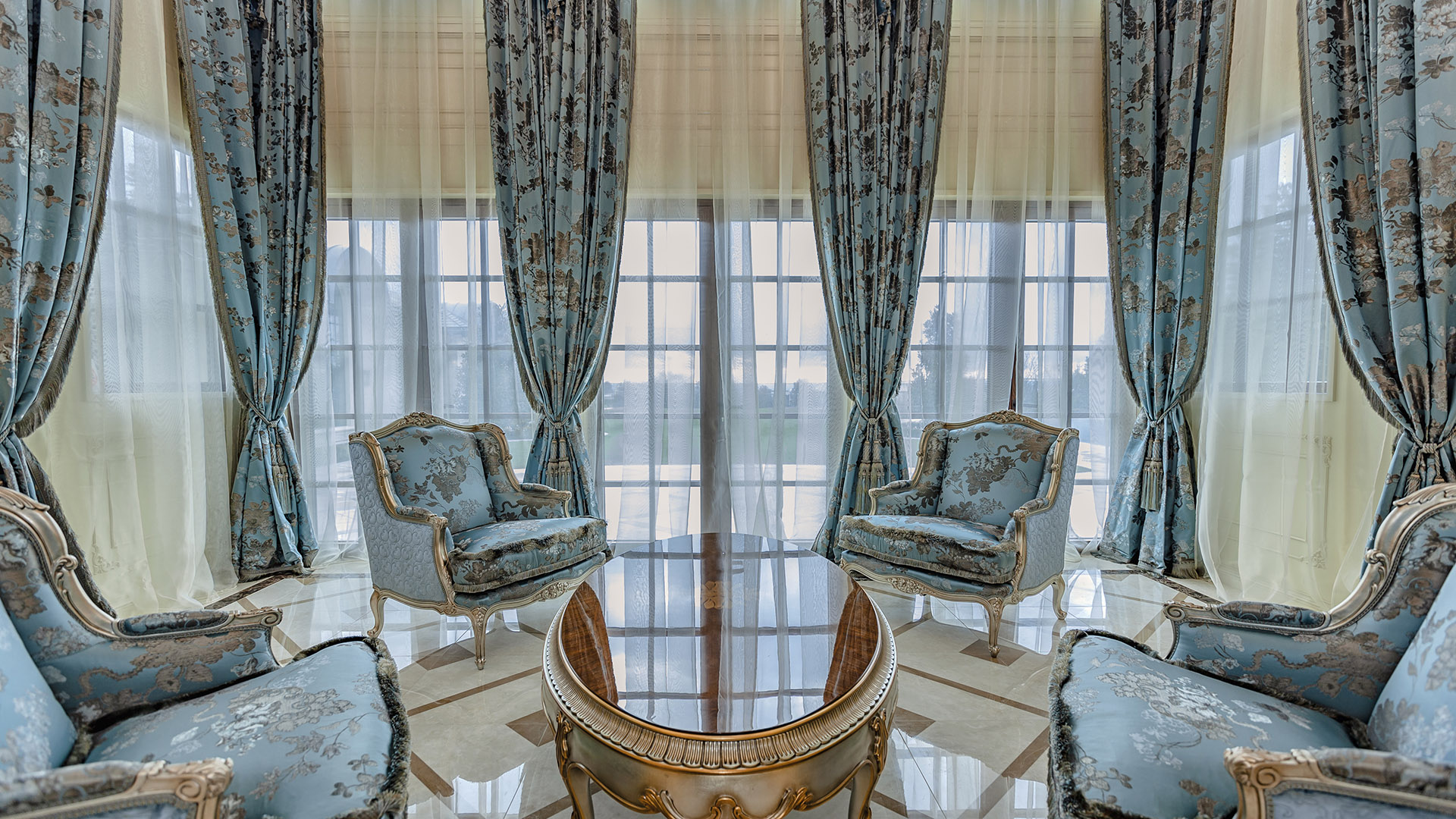 Ambleside Palace sitting area with brocade silk bergère chairs and full-height French windows in West Vancouver