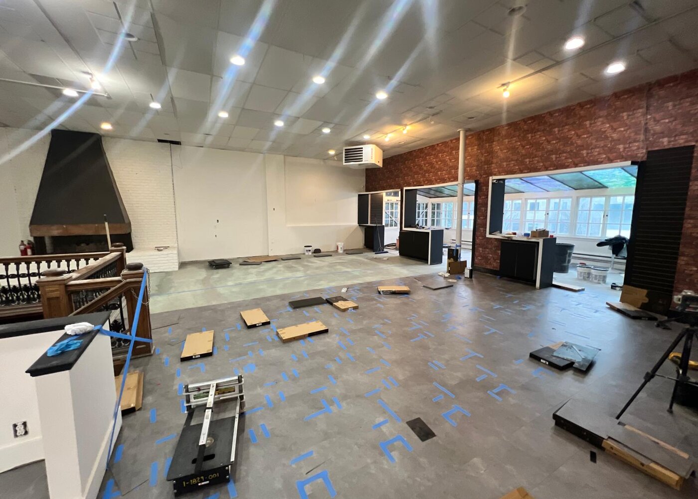 Full view of restored retail interior showing brick walls, decorative fireplace, cabinetry, and new flooring installation in progress