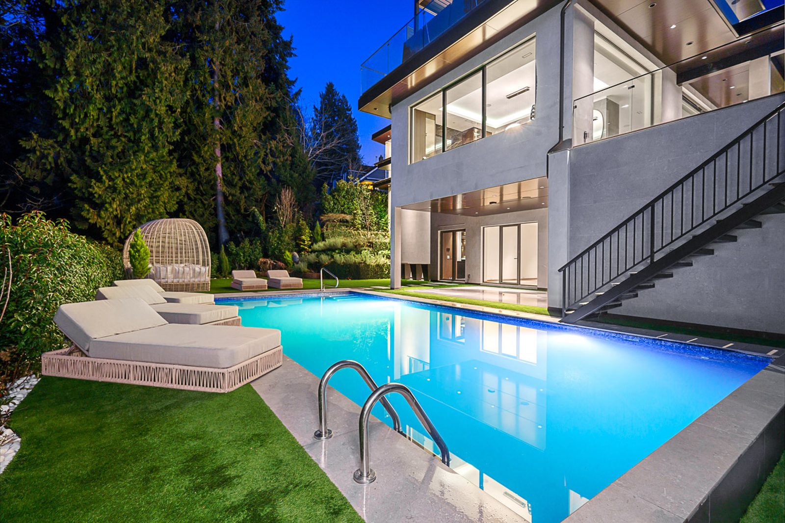 Resort-style swimming pool with glass mosaic tiles sun loungers and rattan egg chair The Butterfly West Vancouver
