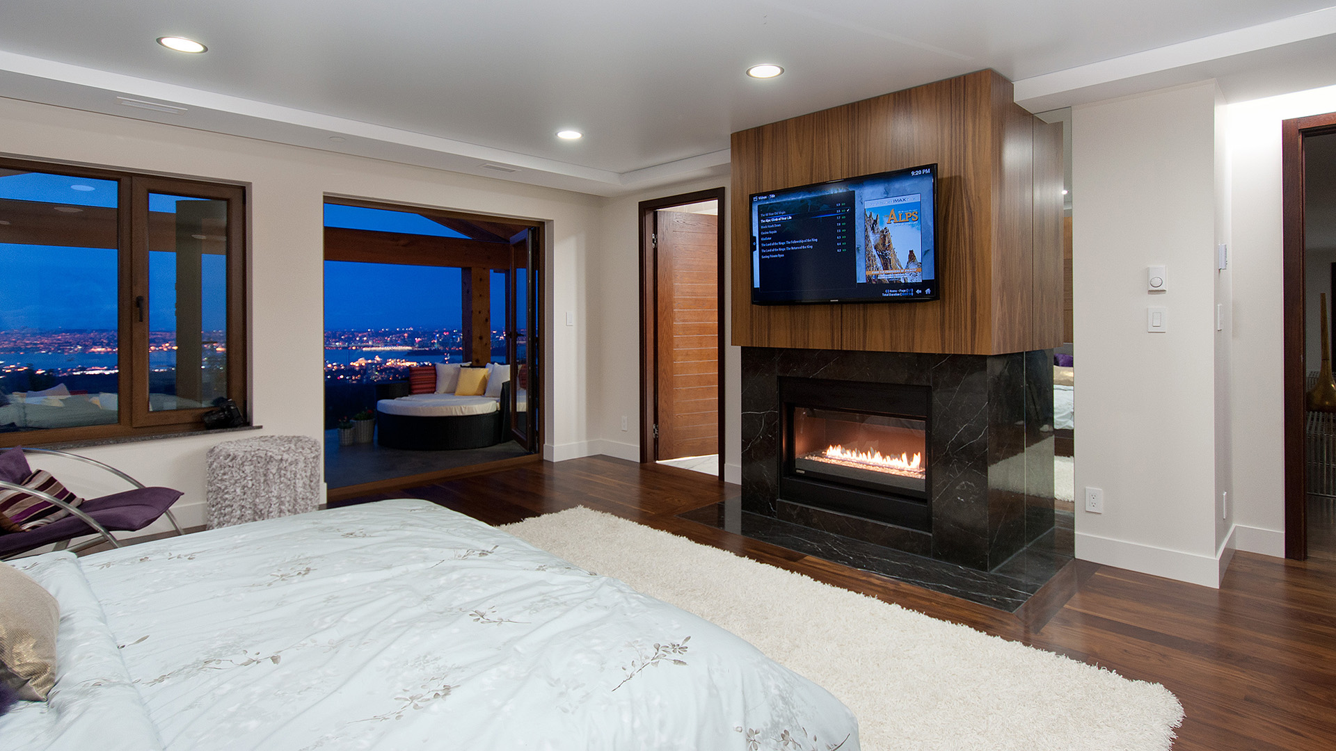 Master bedroom with walnut-panelled gas fireplace marble surround private balcony city views and walnut flooring Millstream British Properties West Vancouver