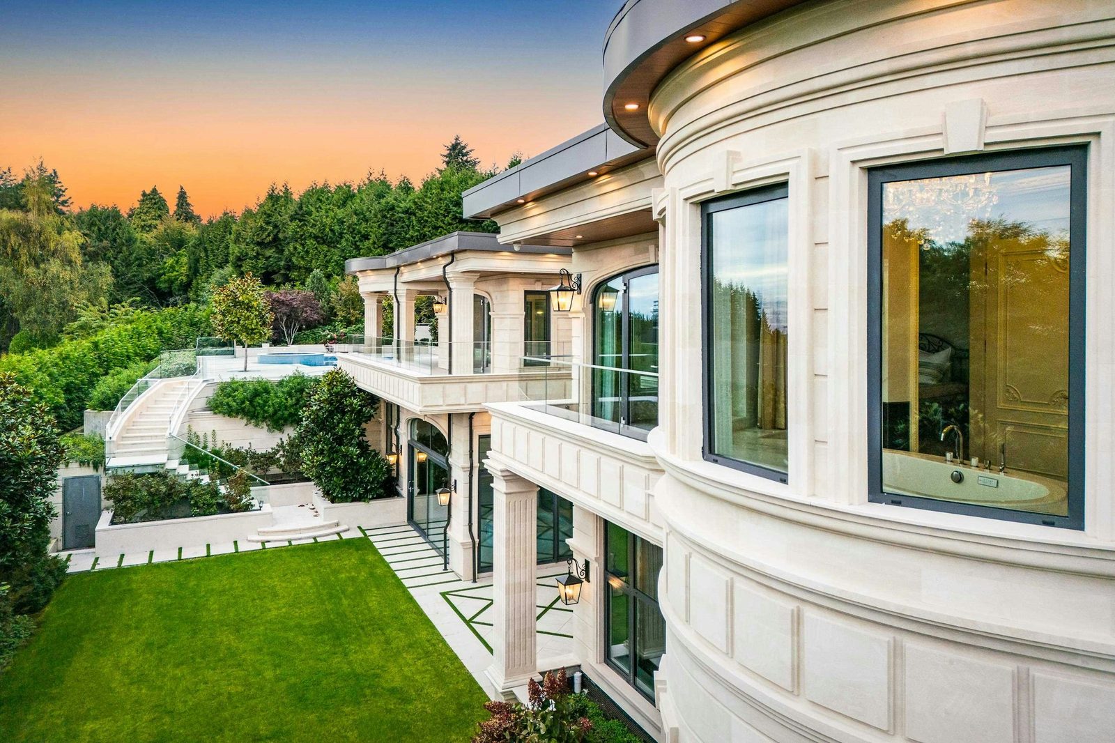 Curved limestone facade of Montbeau Eyremount estate at dusk in West Vancouver