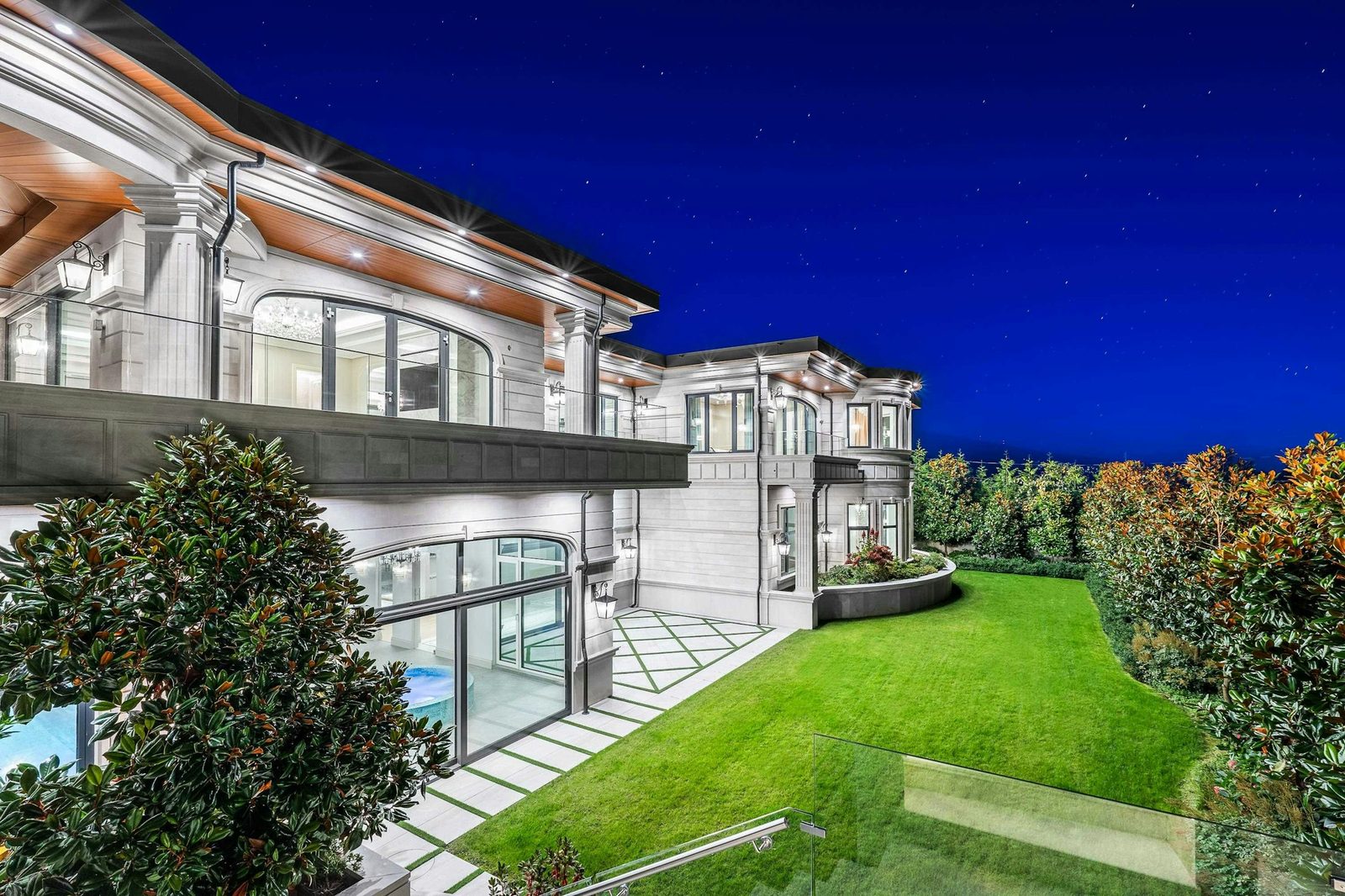 Night view of stone-clad luxury residence with glass railings on Eyremount Drive