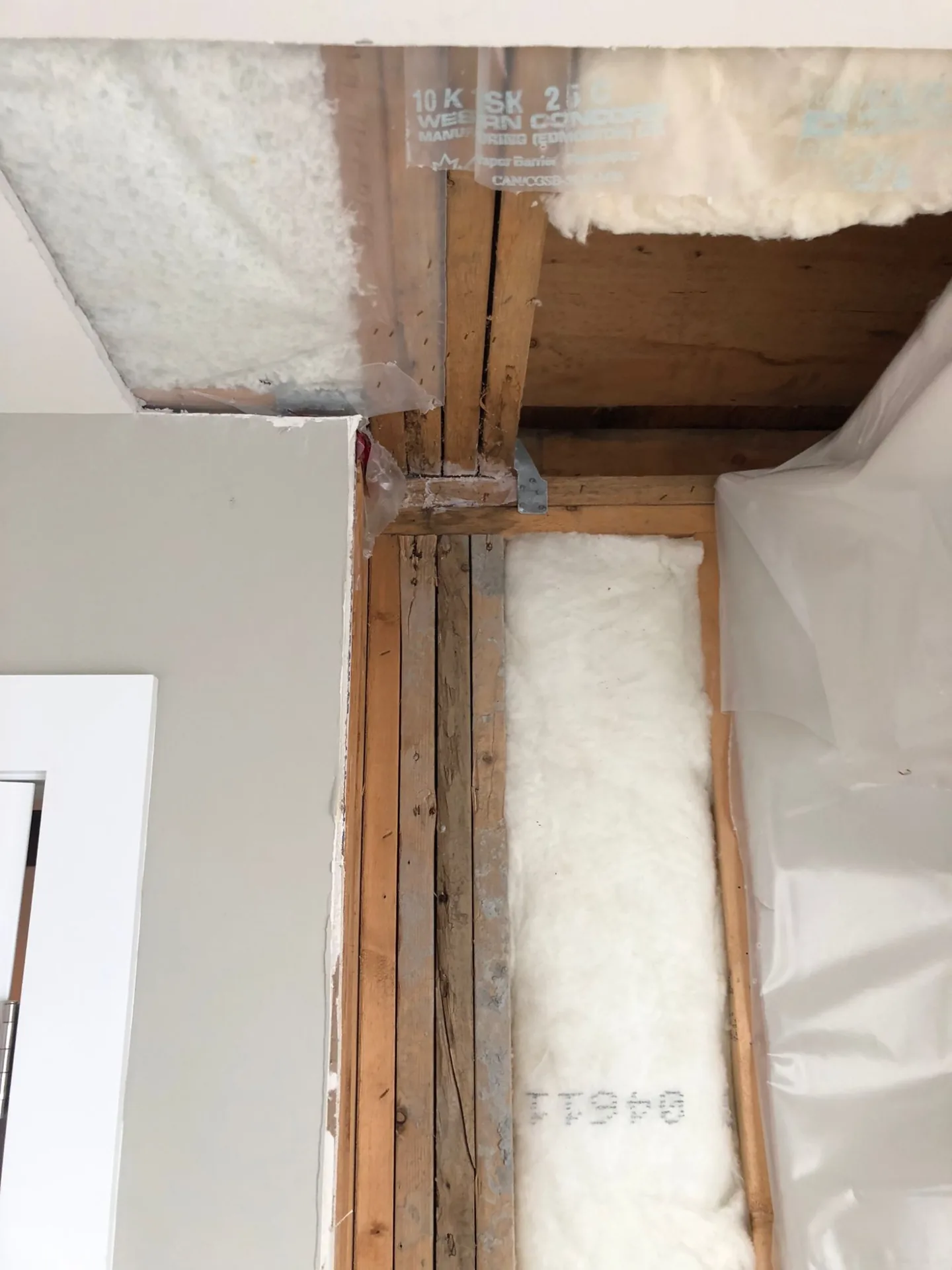 Exterior wall of a North Vancouver strata opened floor to ceiling during water ingress repair, showing framing and new insulation being installed