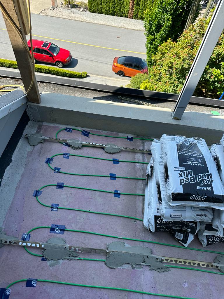 Electric snow melting heating cables installed on balcony deck membrane at Newdale Court with Mapei mud bed mix staged for tile installation