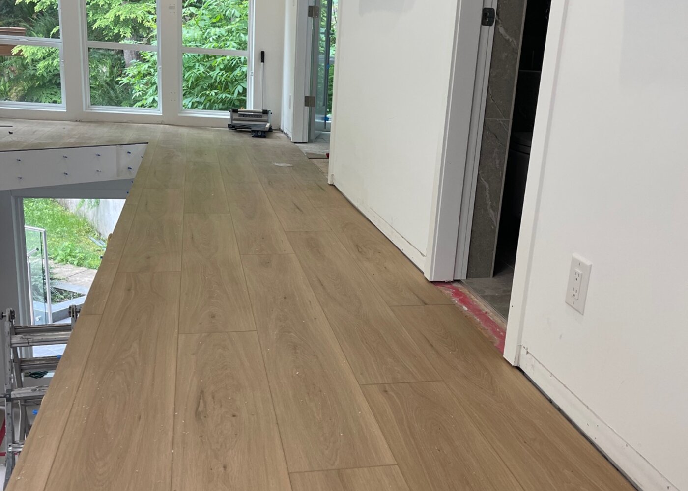 New laminate flooring installed in hallway running toward windows and kitchen area with clean baseboard transitions — insurance restoration result
