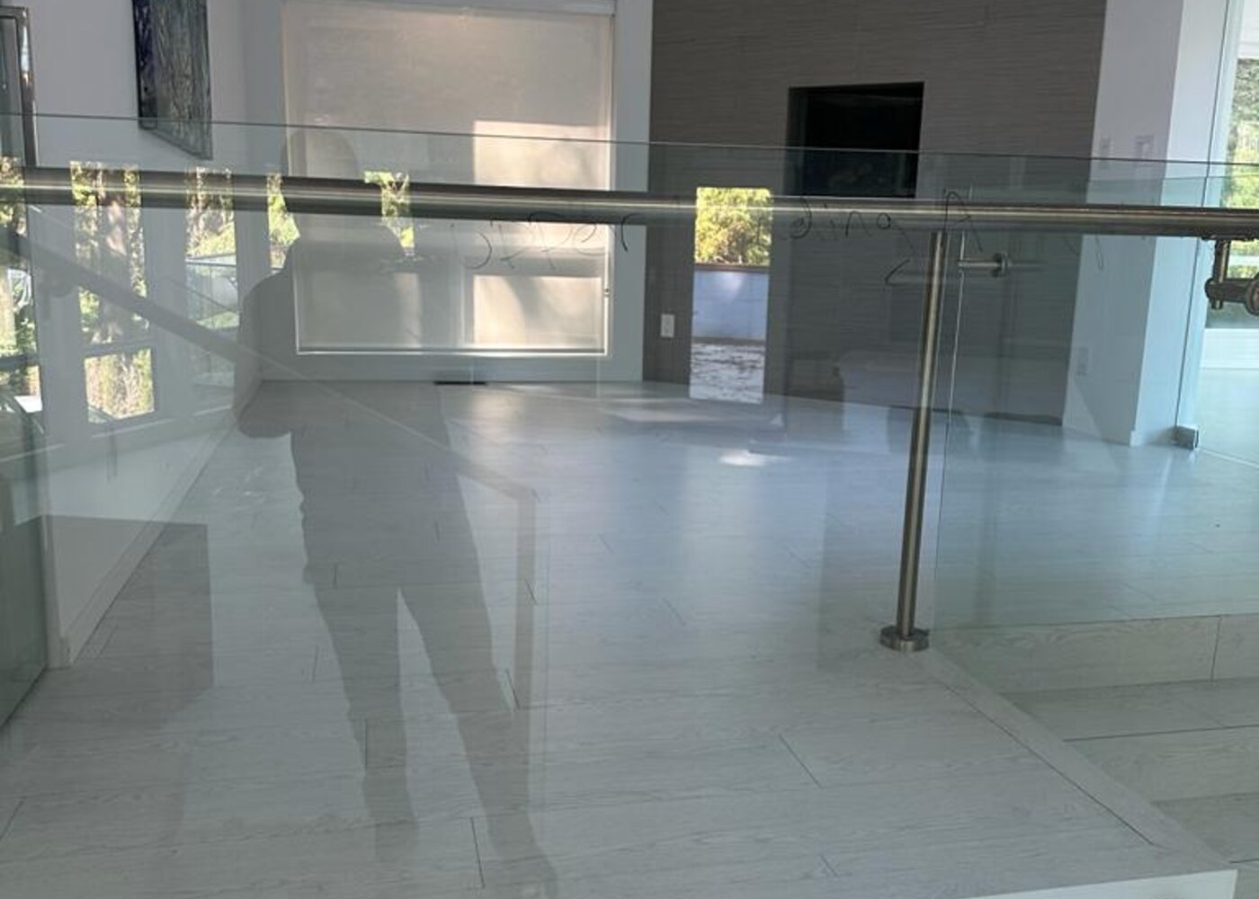 Living room with skylight, vaulted ceiling, and fireplace feature wall through glass railing — luxury home before storm damage