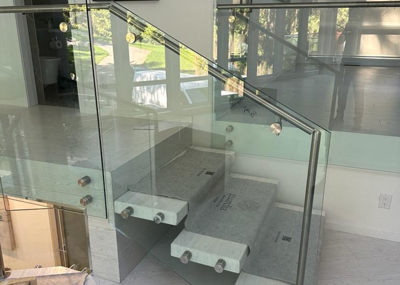 Glass railing hardware detail on floating staircase before restoration at Prospect Road North Vancouver