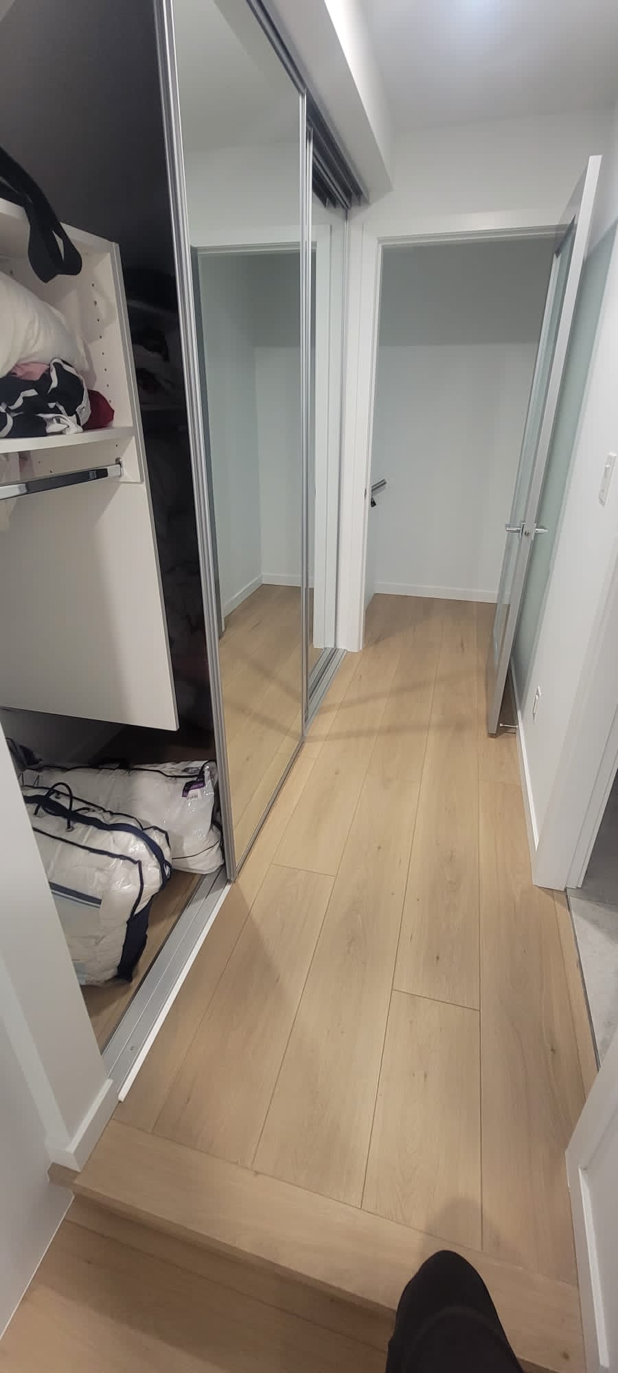 Walk-in closet with new laminate flooring and sliding mirror doors at Prospect Road North Vancouver by Eurohouse Construction