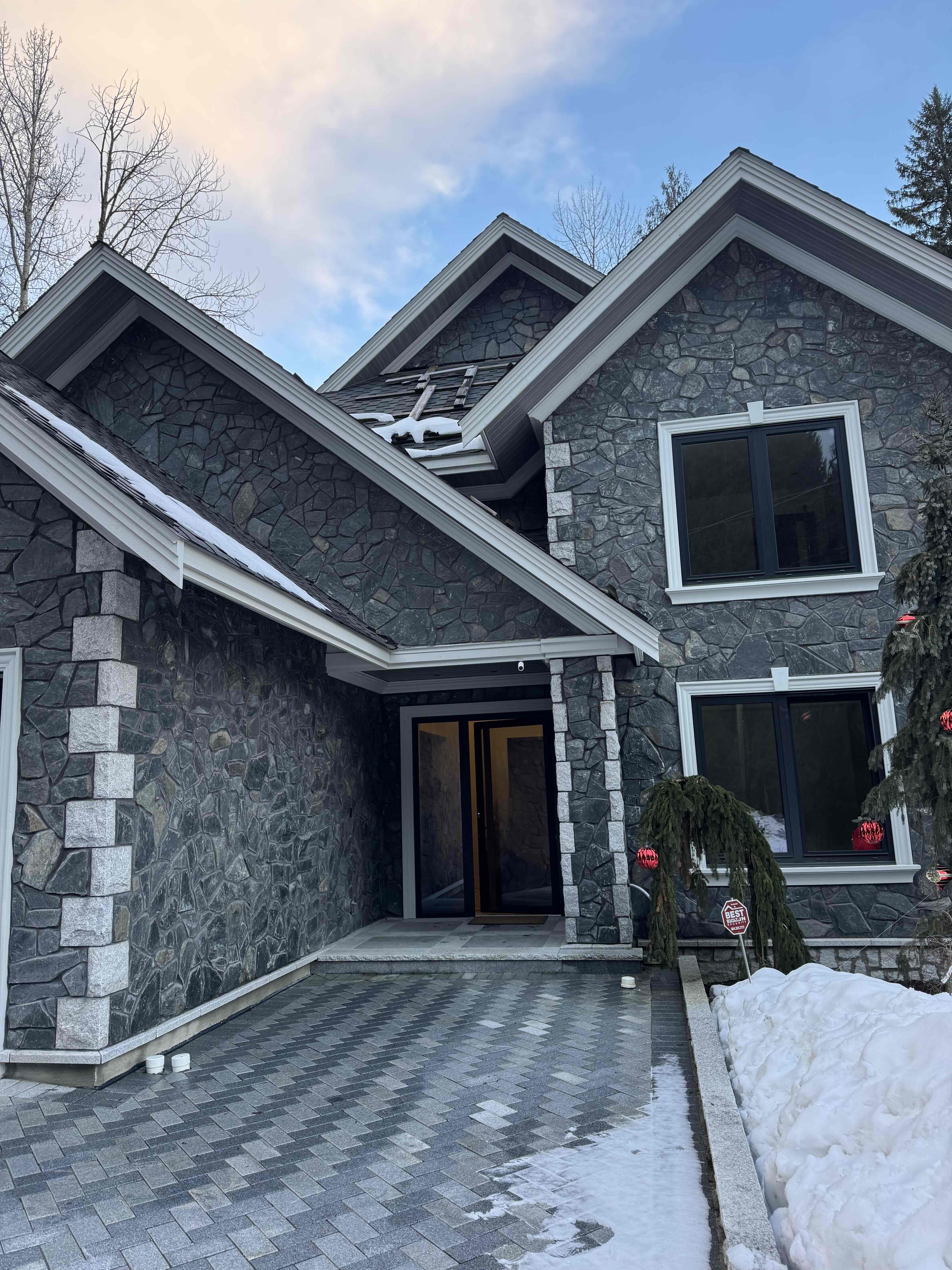 Main entrance of Rainbow in Whistler — stone columns, herringbone paver walkway, and gabled entry portico built by Eurohouse Construction