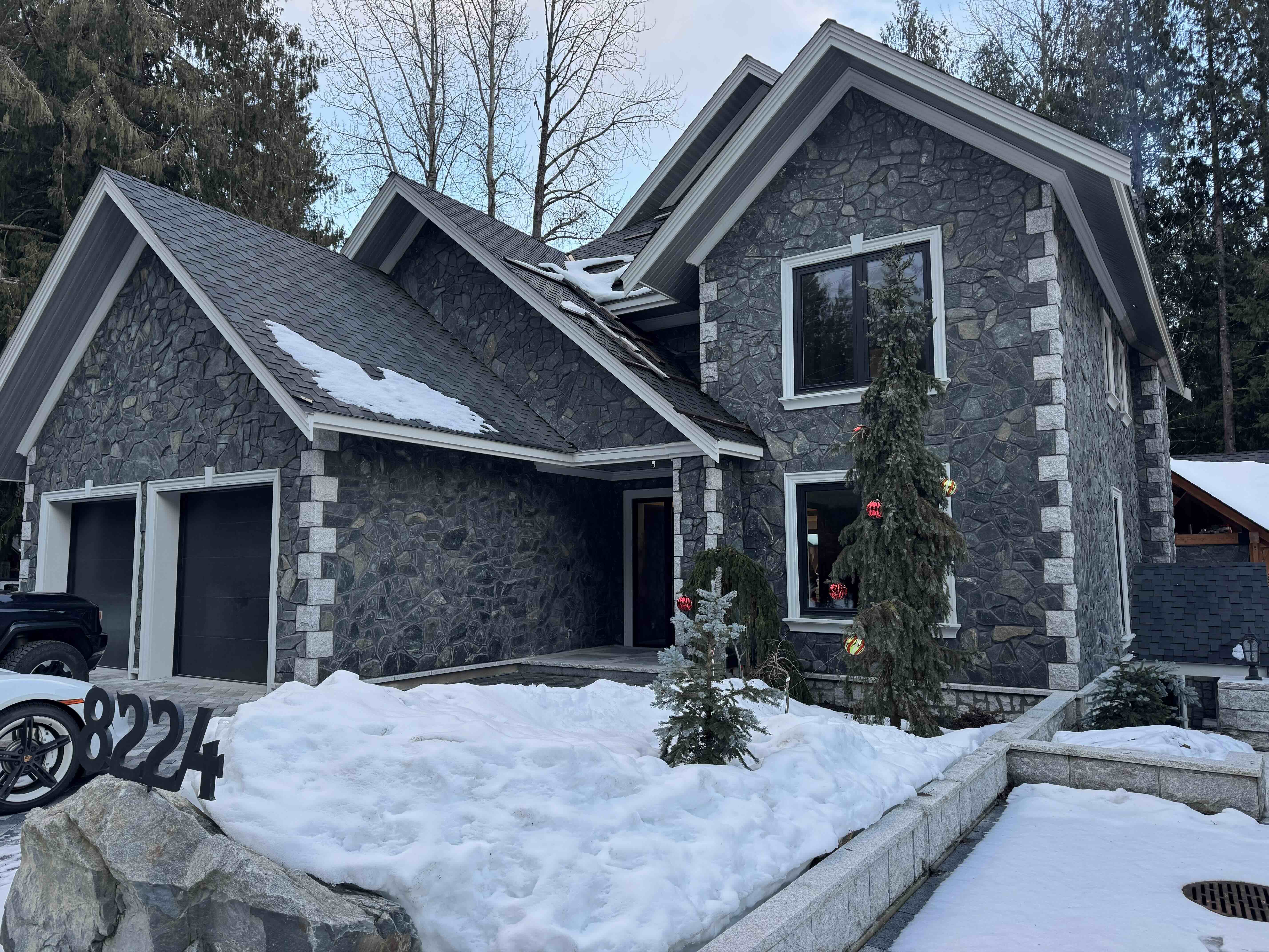Rainbow in Whistler — luxury ICF concrete custom home with full natural stone facade, double garage, and snow-covered mountain setting built by Eurohouse Construction