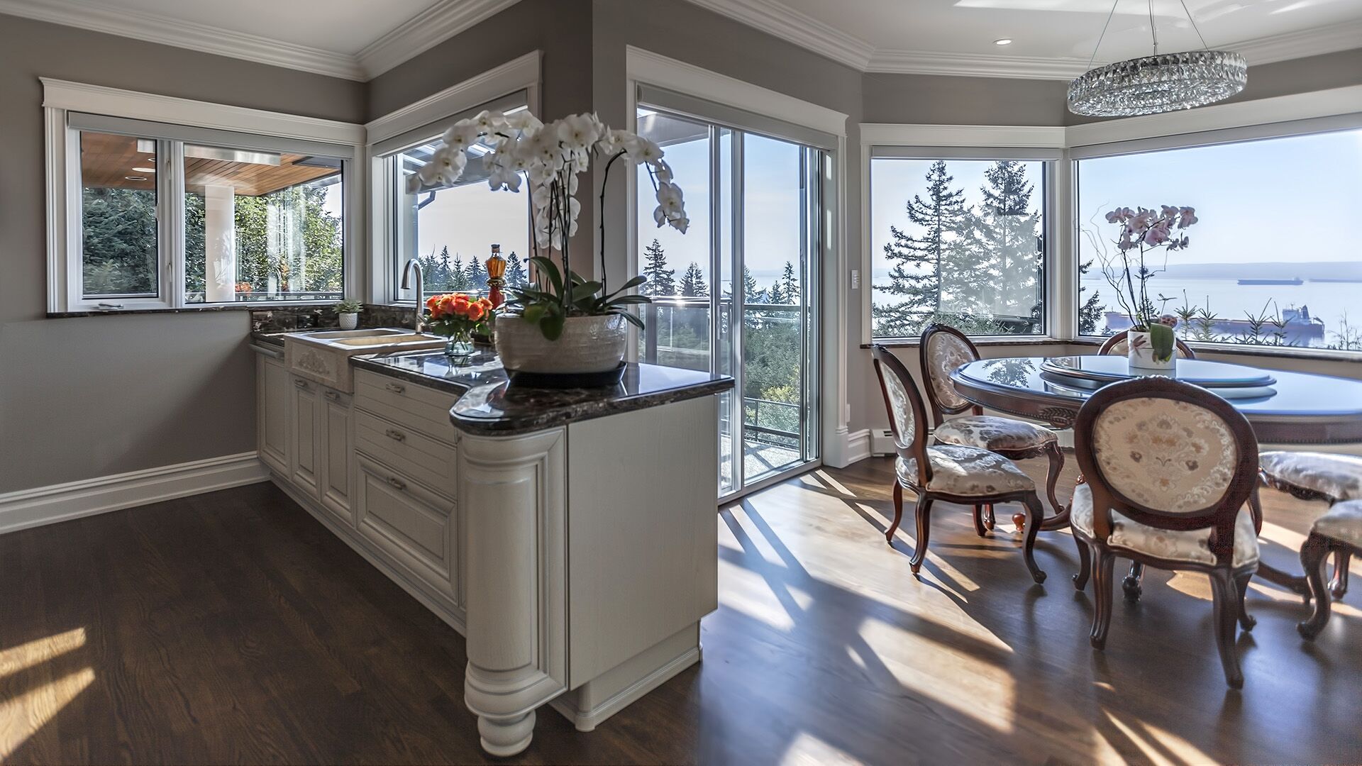 Breakfast nook with bay window ocean views crystal drum chandelier Louis XVI French Provincial chairs farmhouse sink island and orchid display at Rockridge Classic built by Eurohouse Construction