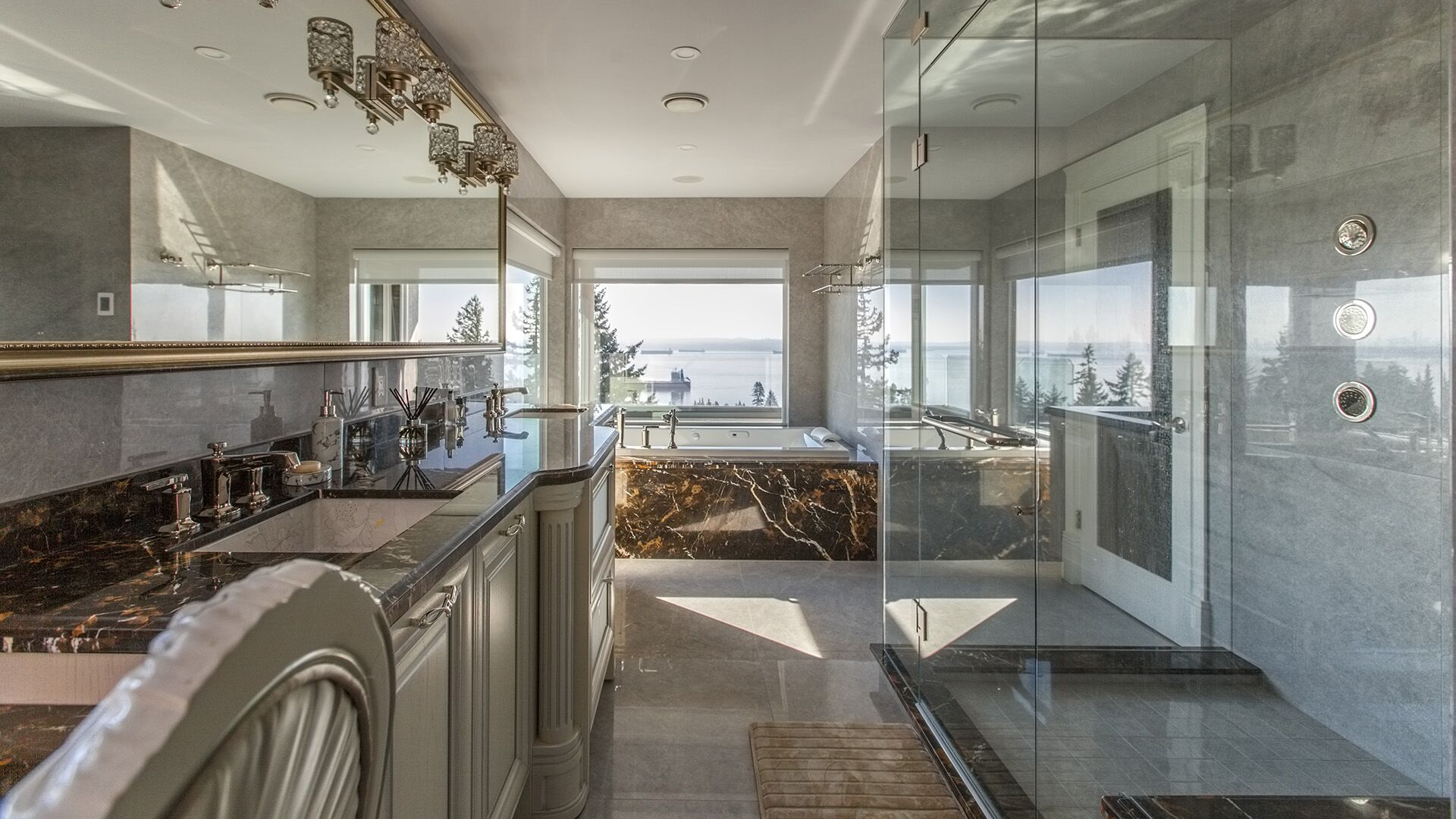 Master ensuite with Emperador Dark marble vanity and soaking tub surround cream raised-panel cabinetry glass shower enclosure crystal sconces and ocean views at Rockridge Classic built by Eurohouse Construction