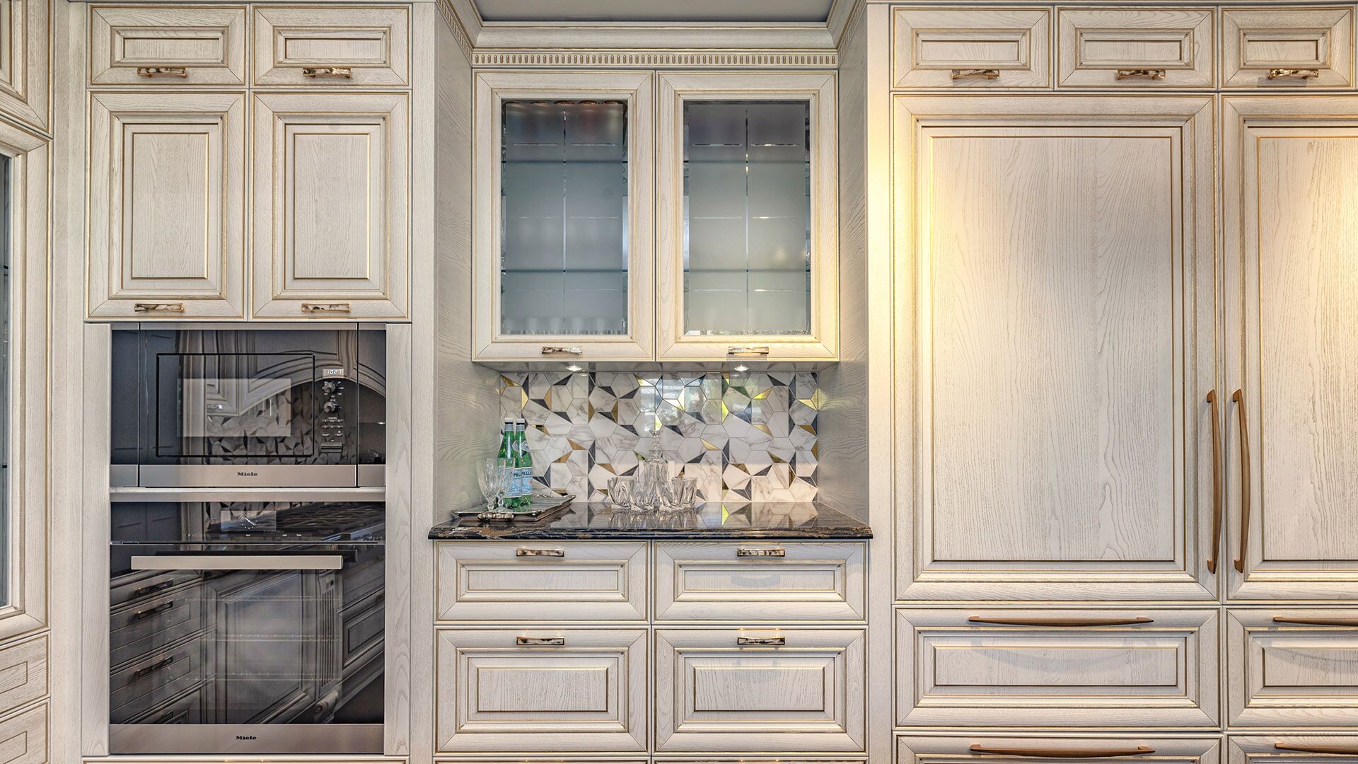 Italian cabinetry wall with integrated Miele double oven, glass display cabinets, and geometric backsplash by Eurohouse Construction West Vancouver