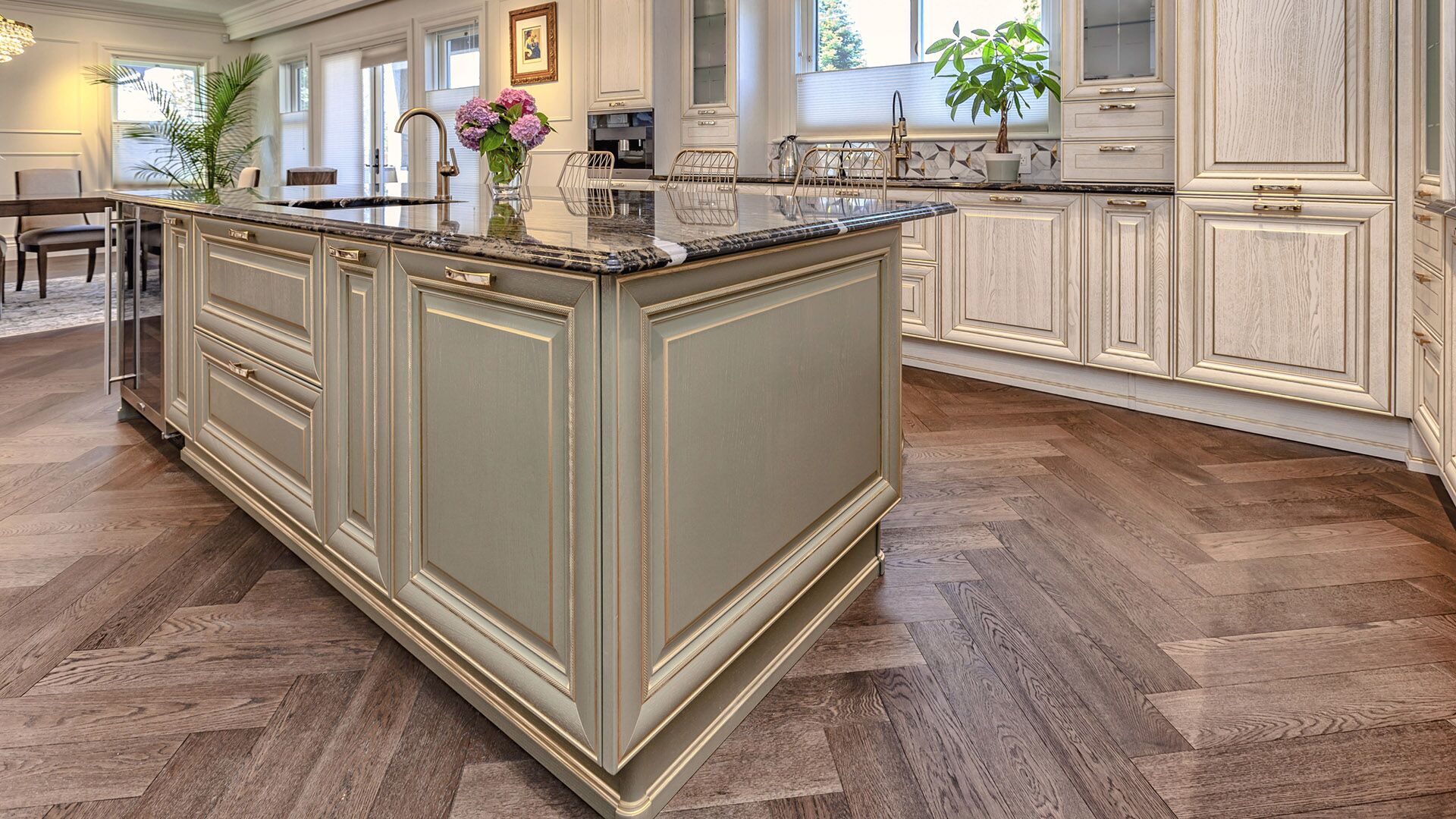Sage-green Italian kitchen island with gold leaf trim, dark granite countertop, and herringbone oak flooring by Eurohouse Construction West Vancouver