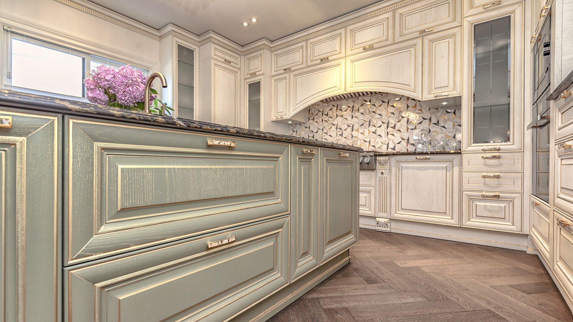 Close-up of sage-green Italian cabinetry with gold leaf detailing and geometric mosaic backsplash by Eurohouse Construction