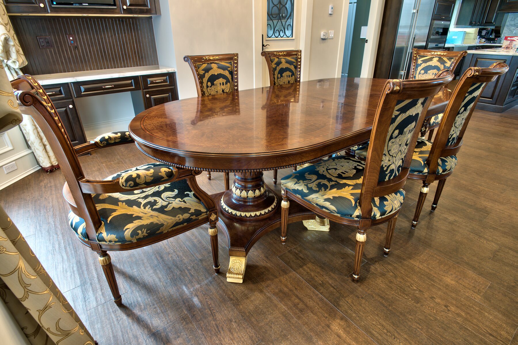 Oval Francesco Molon pedestal dining table with patterned upholstered chairs and gold curtains in a Vancouver home furnished by Eurohouse Construction