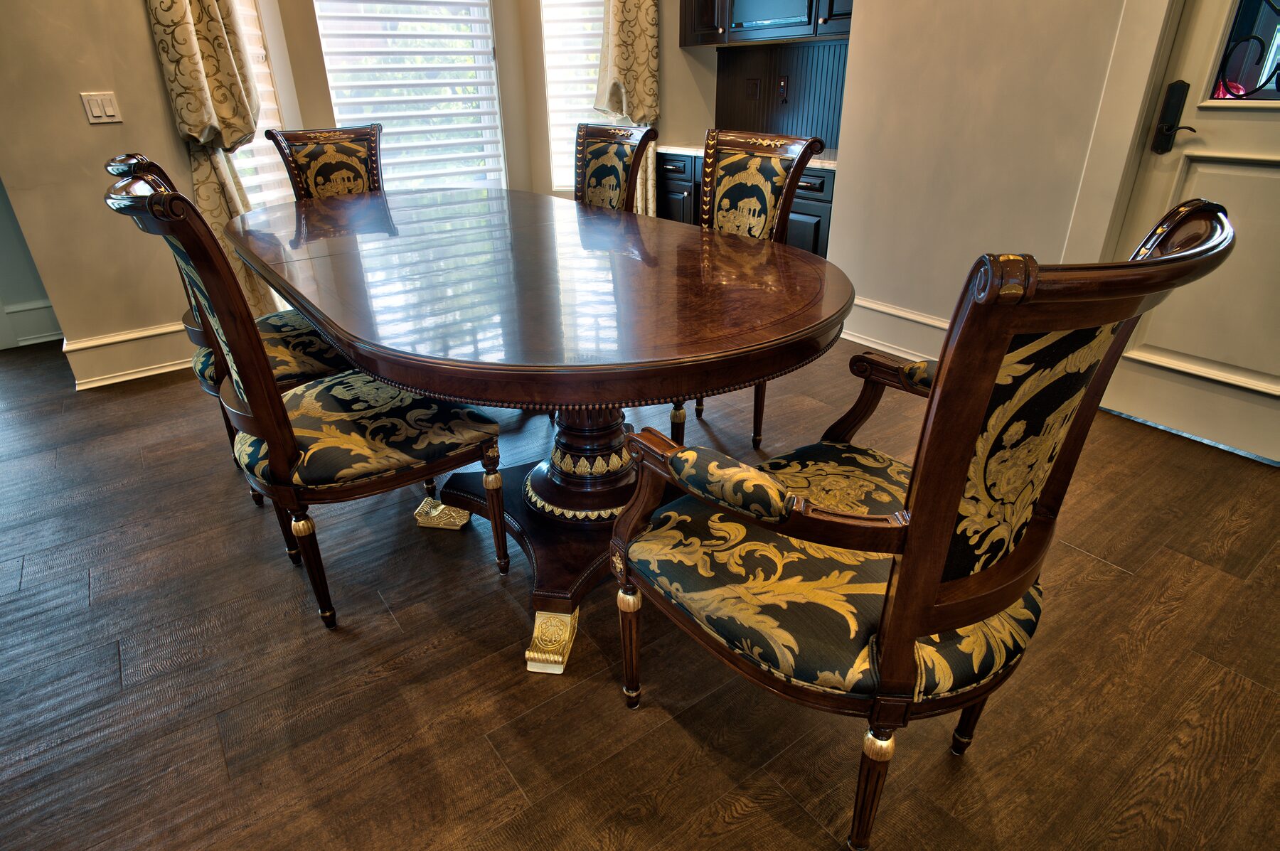 Oval Francesco Molon dining table on a carved gilded pedestal with teal and gold upholstered chairs in a Vancouver home furnished by Eurohouse Construction