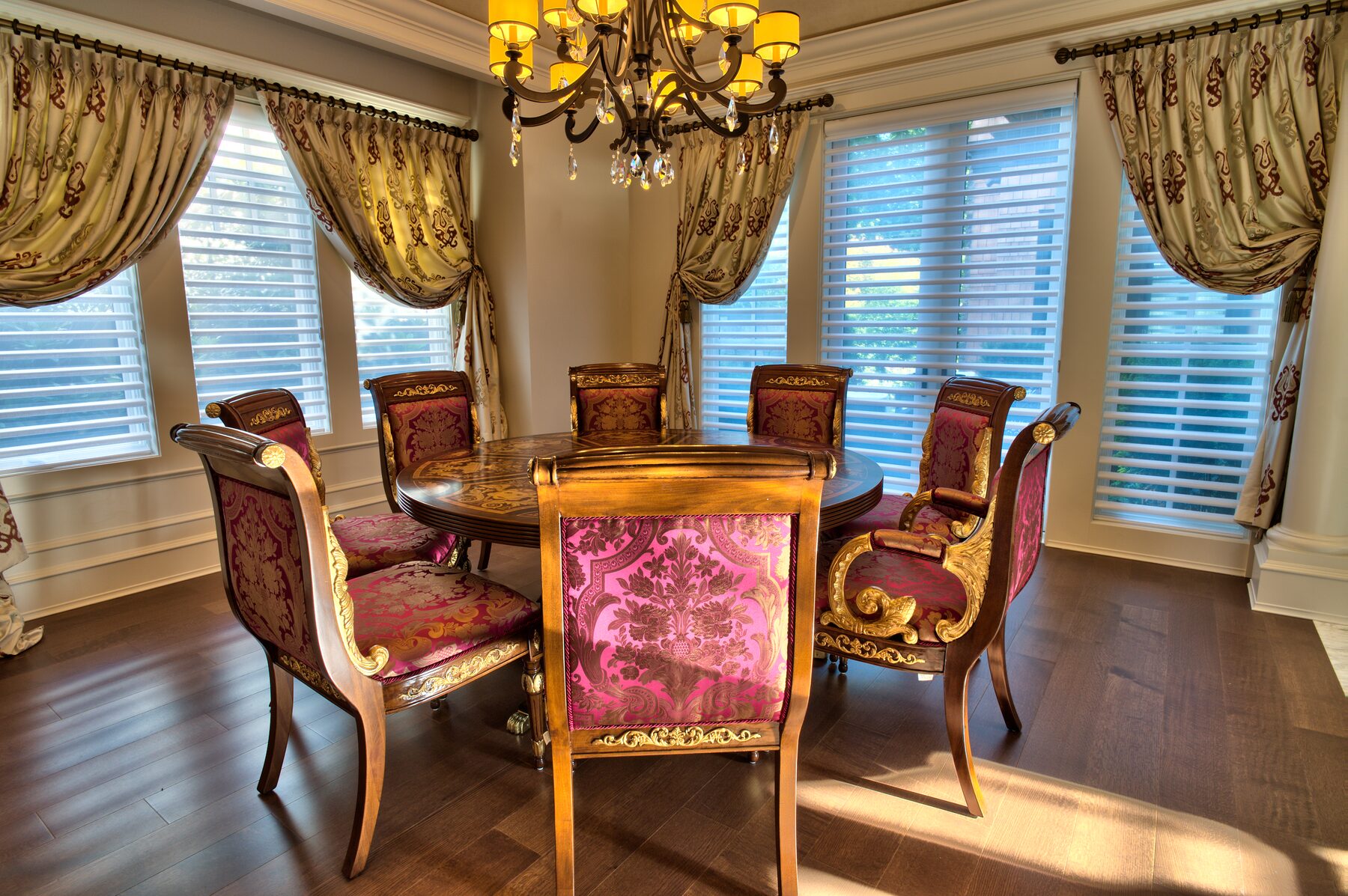 Round Francesco Molon dining table with carved chairs and gold drapery beside a staircase in a Vancouver home furnished by Eurohouse Construction