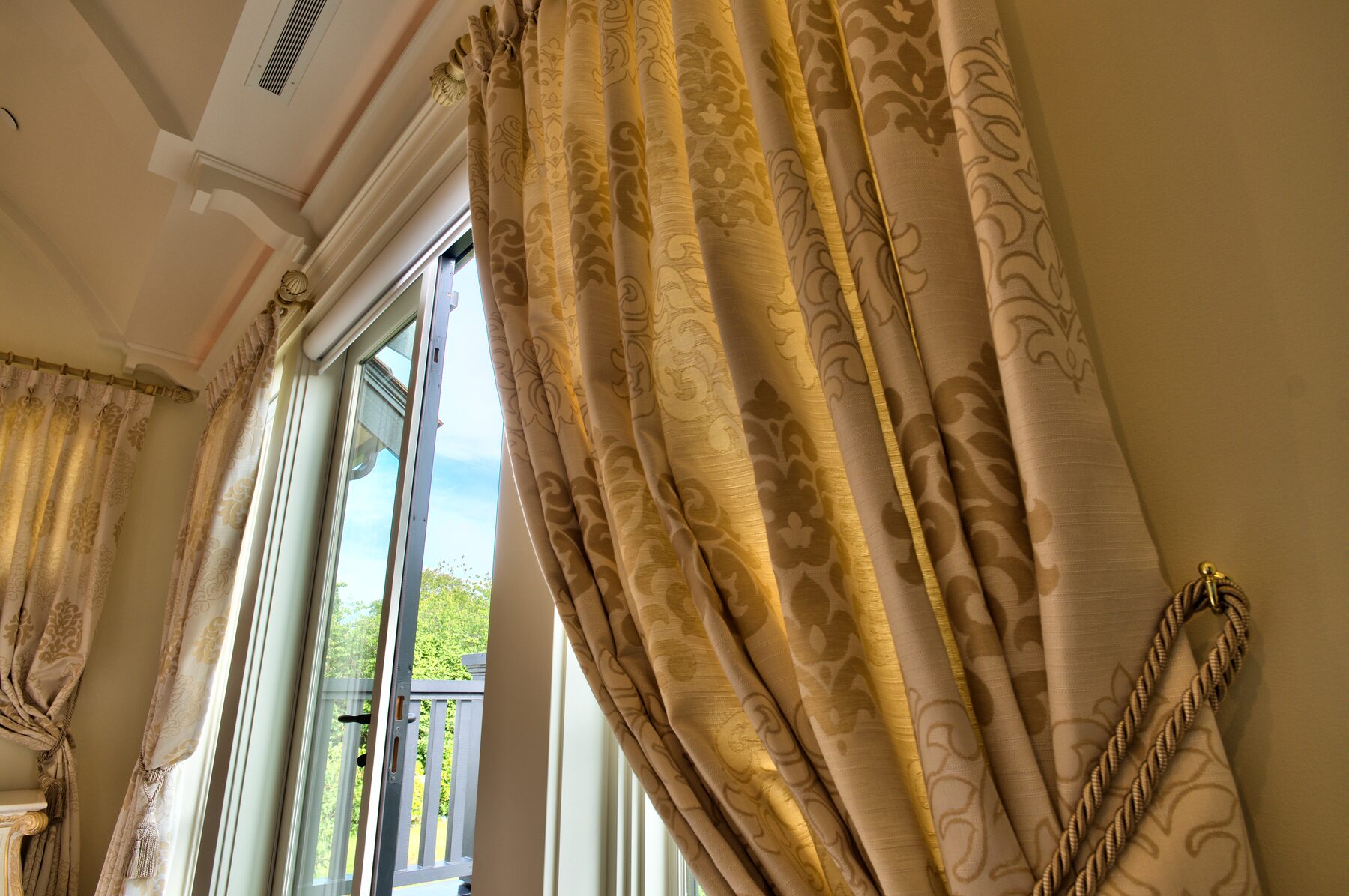 Full height gold drapery with tieback and pooled hem at a tall window in a Vancouver home furnished by Eurohouse Construction