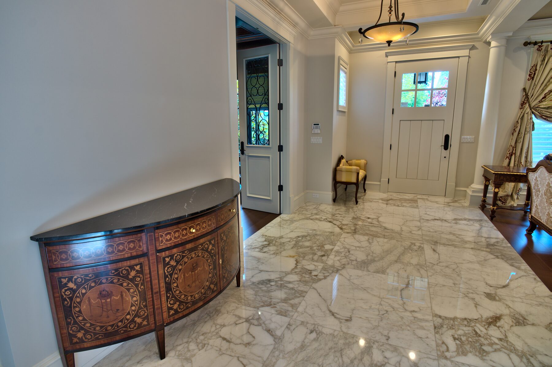 Inlaid Francesco Molon credenza on a white marble floor in the entry hall of a Vancouver home furnished by Eurohouse Construction