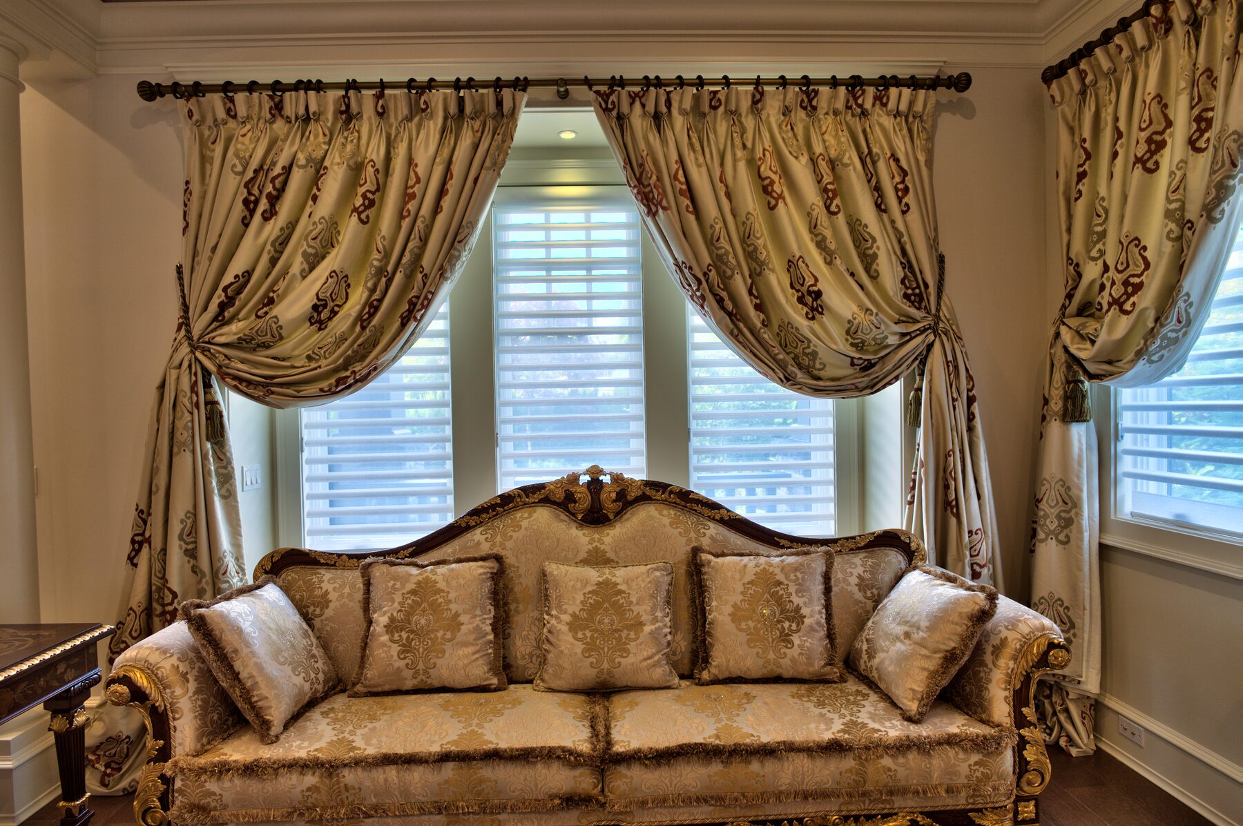 Long Francesco Molon sofa in gold damask beneath a swagged and tailed drapery treatment in a Vancouver home furnished by Eurohouse Construction
