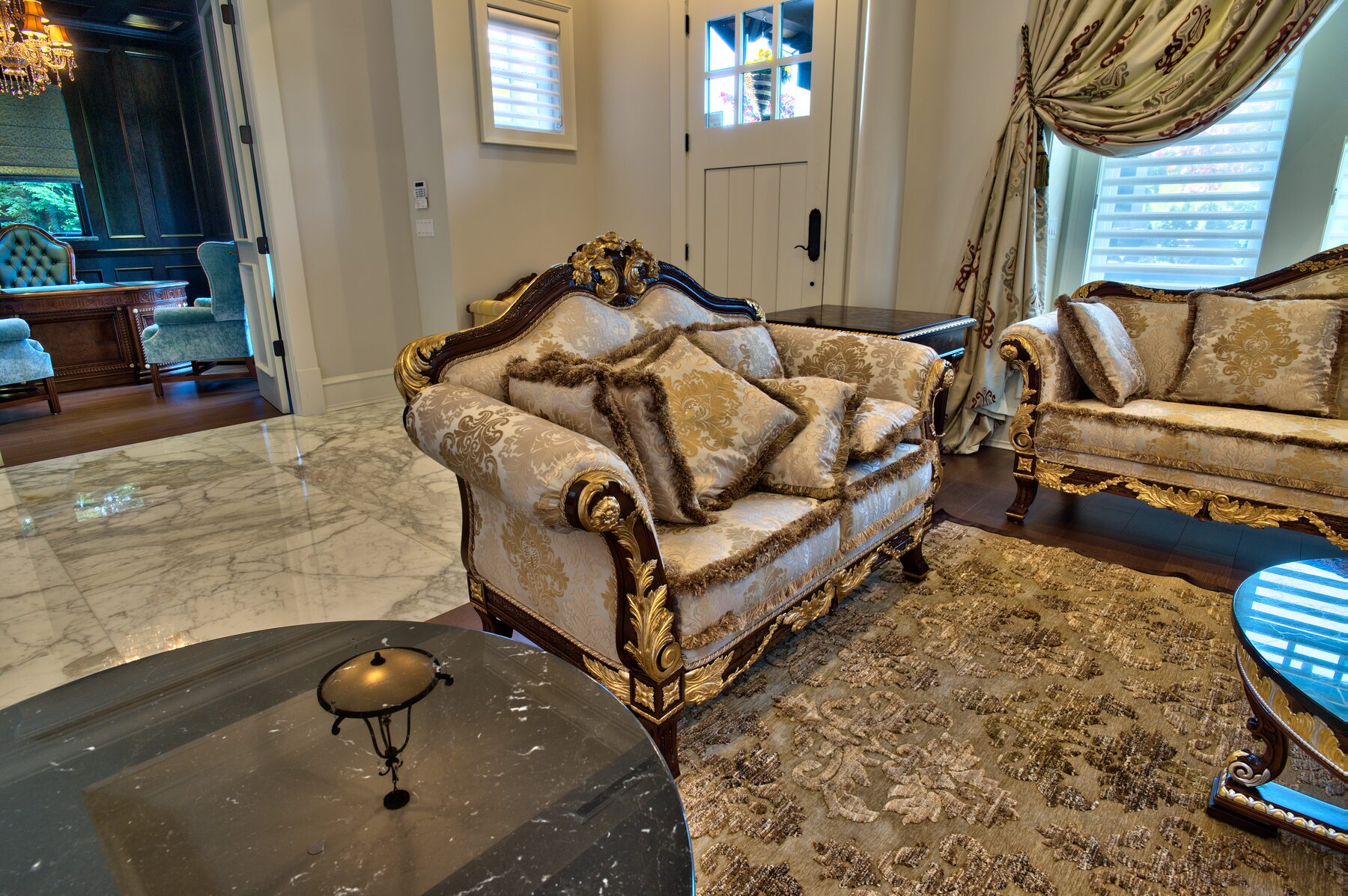 Carved Francesco Molon settee in pale silk damask on a marble floor with area rug near the entry of a Vancouver home furnished by Eurohouse Construction