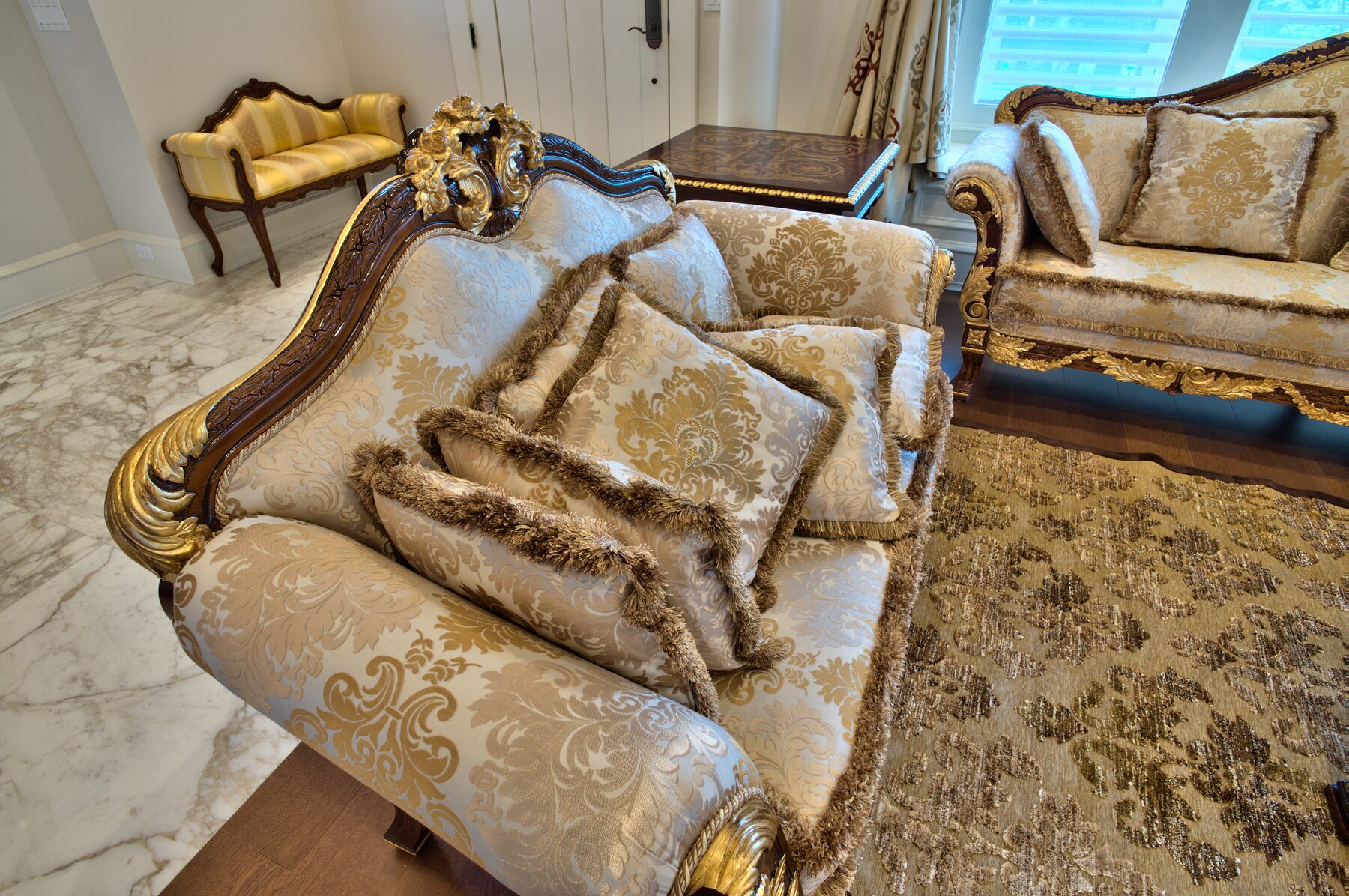 Detail of gold and cream damask upholstery with carved gilded frame on a Francesco Molon sofa in a Vancouver home furnished by Eurohouse Construction