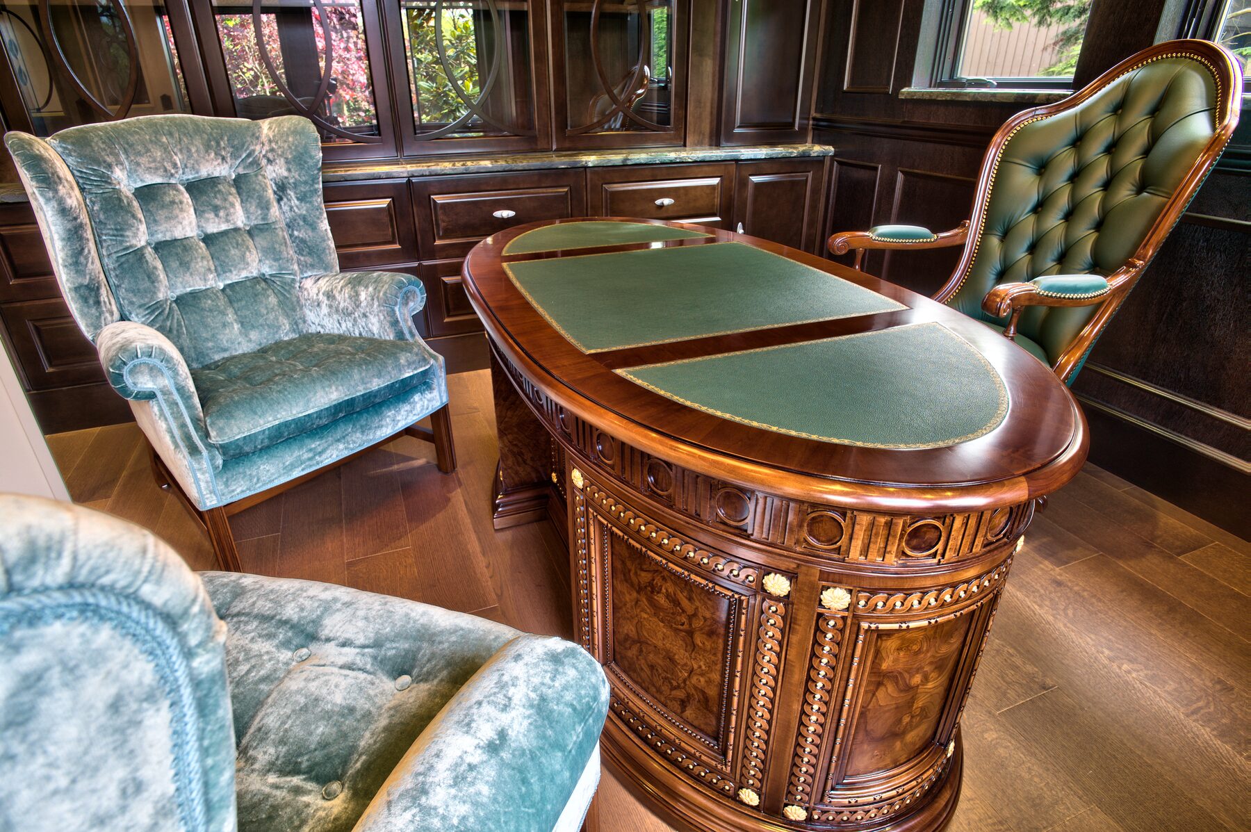 Detail of an inlaid Francesco Molon desk with green leather top and carved gilt mounts beside a velvet armchair in a Vancouver study furnished by Eurohouse Construction