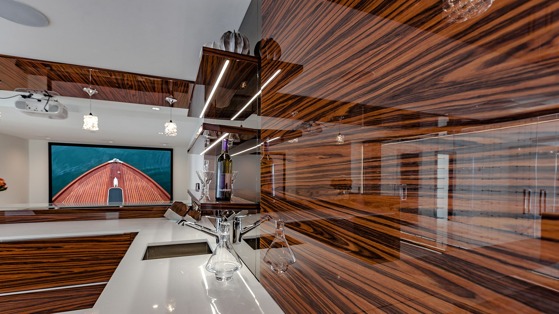 Close-up of zebrawood bar with Riva boat bow projected on screen LED shelf lighting wine display and chrome fixtures at The Riva Club designed and installed by Eurohouse Construction