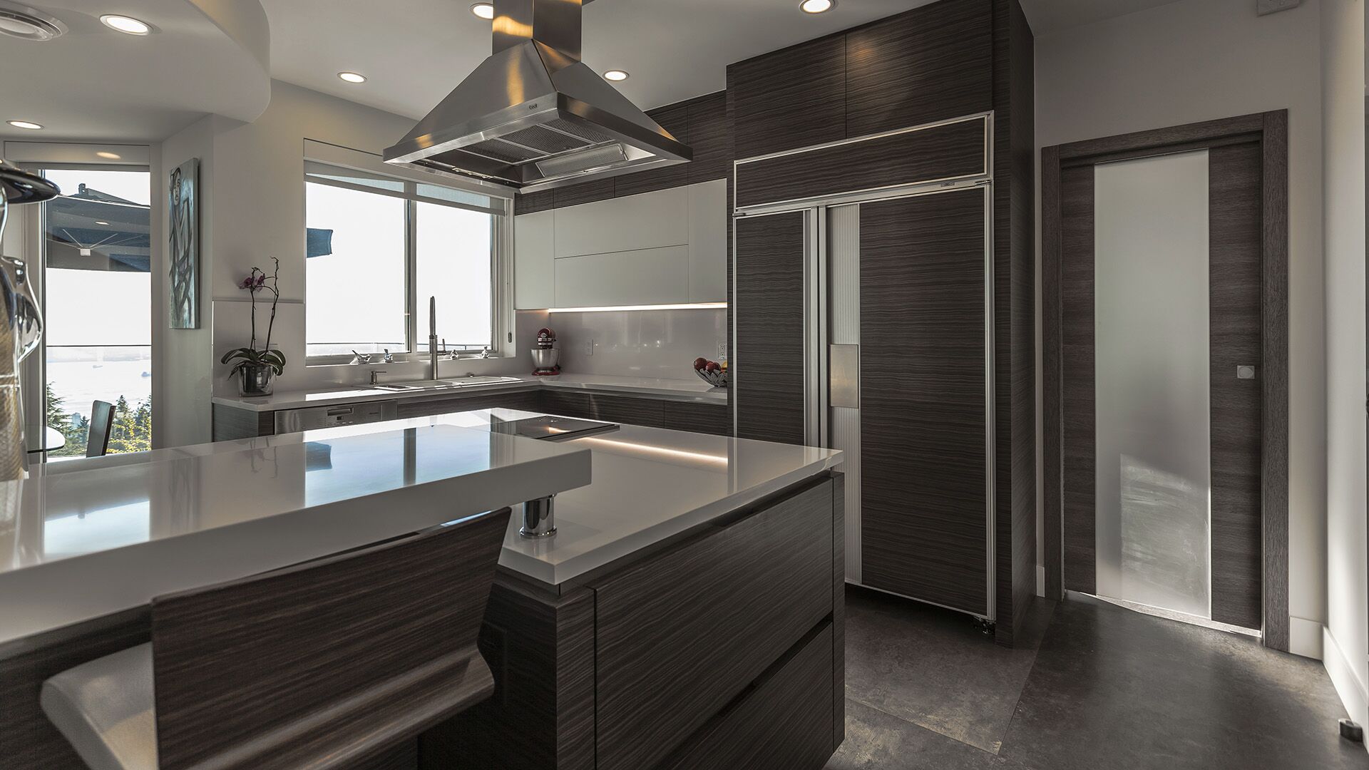 Kitchen detail showing Italian dark veneer cabinetry panel-integrated refrigerator white quartz countertop matching Italian interior doors at The Zen on Bramwell renovated by Eurohouse Construction
