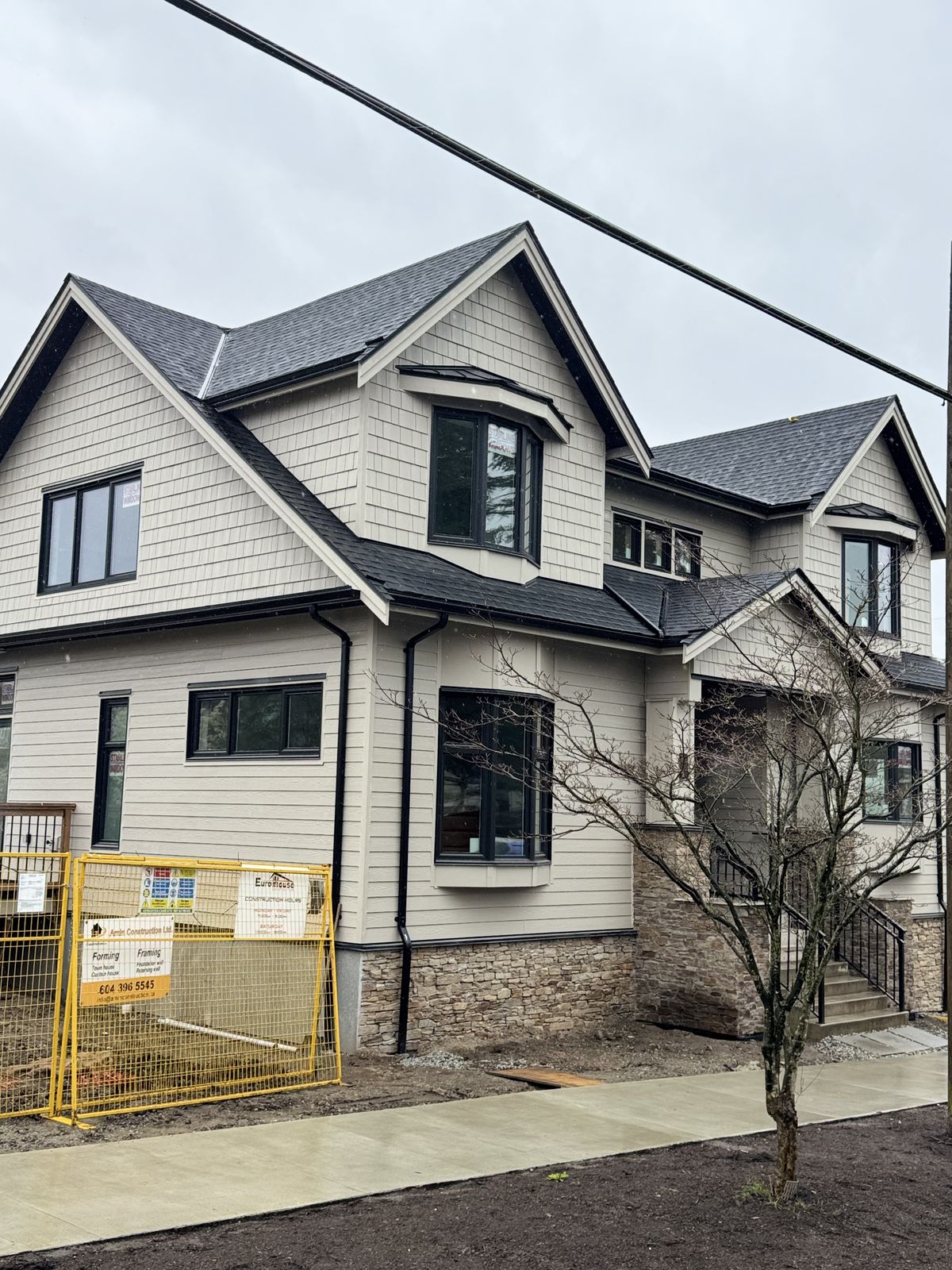 Front elevation of completed fire restoration rebuild — Hardie siding, stone accents, new windows and roofing Vancouver