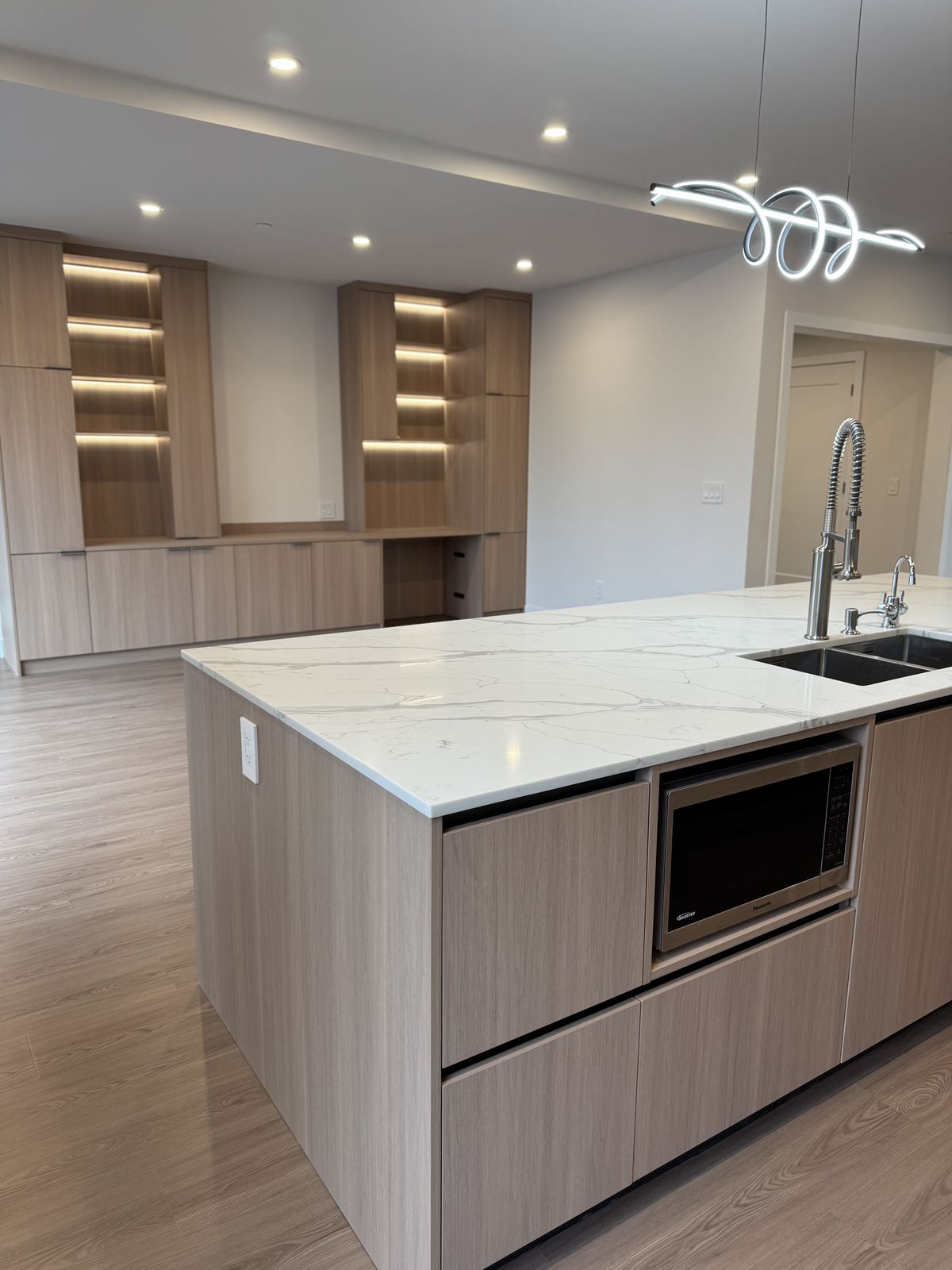 Kitchen island and custom built-in wall unit with LED accent shelving — fire damage rebuild Vancouver
