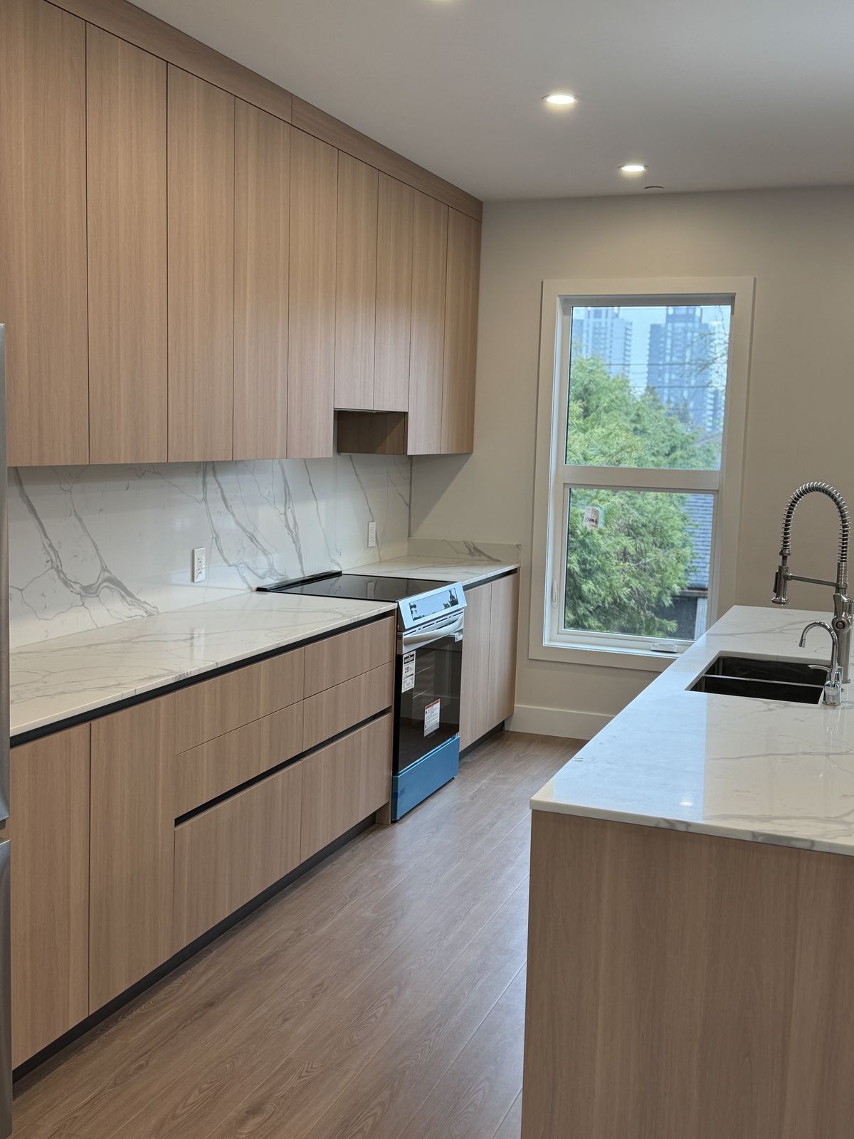 Full kitchen run with walnut cabinetry, marble backsplash, and integrated appliances — insurance restoration Vancouver