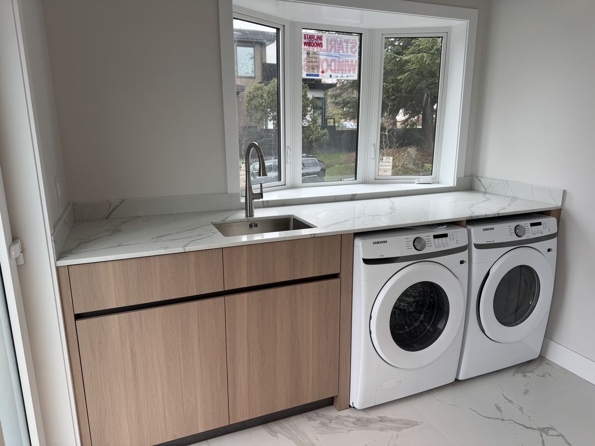 Laundry room with marble countertop, walnut cabinetry, and undermount sink — fire restoration Vancouver