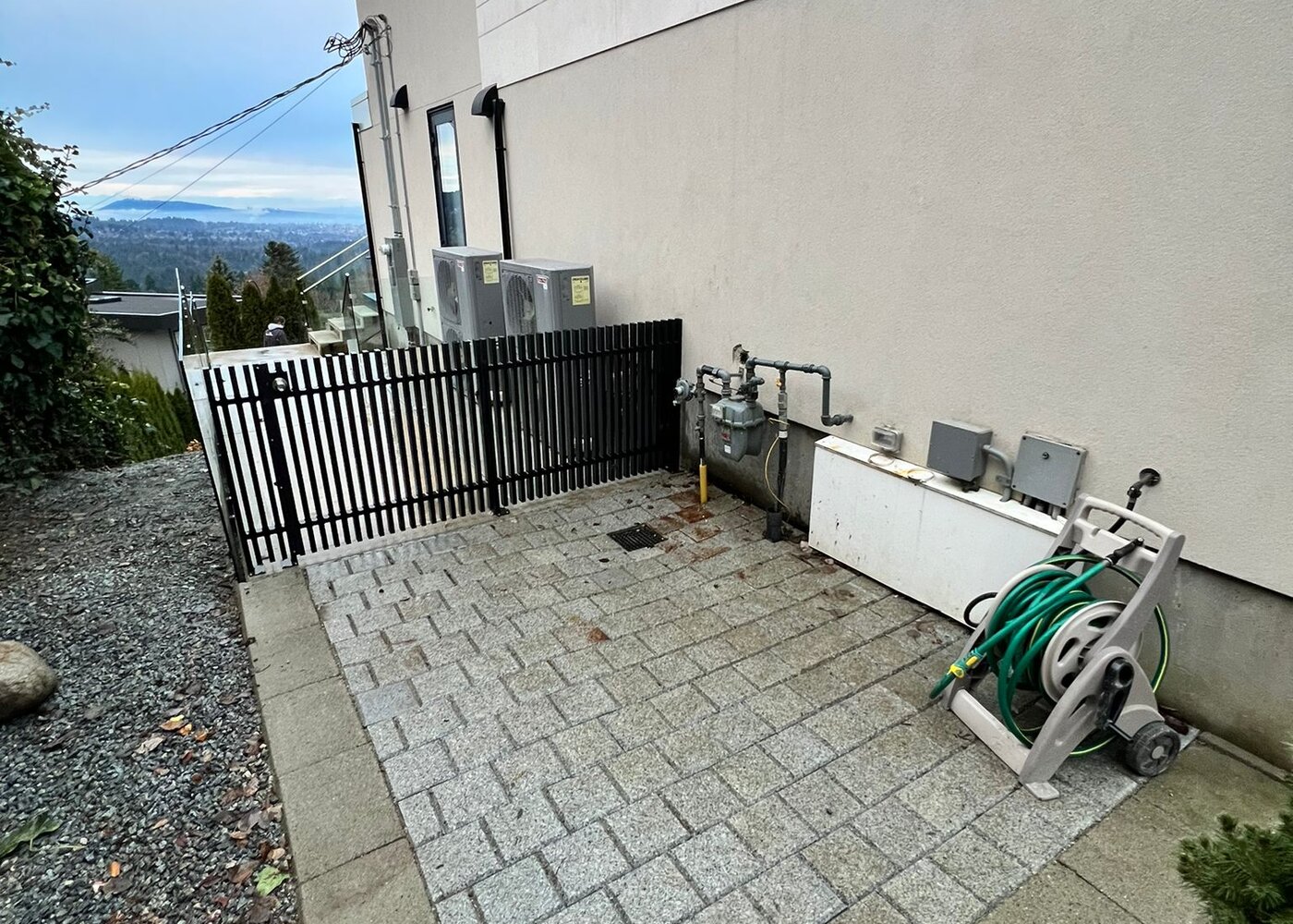 Completed exterior restoration showing restored paver walkway, gas meters, and HVAC units along West Vancouver home
