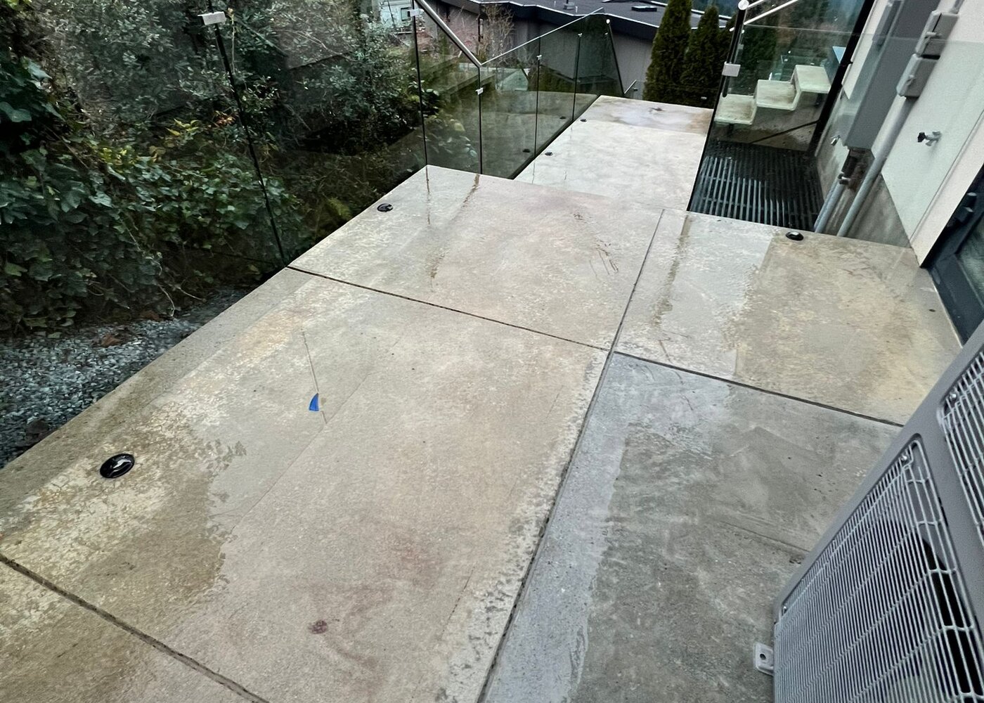 Restored concrete terrace with glass railing and ocean views after foundation repair in West Vancouver
