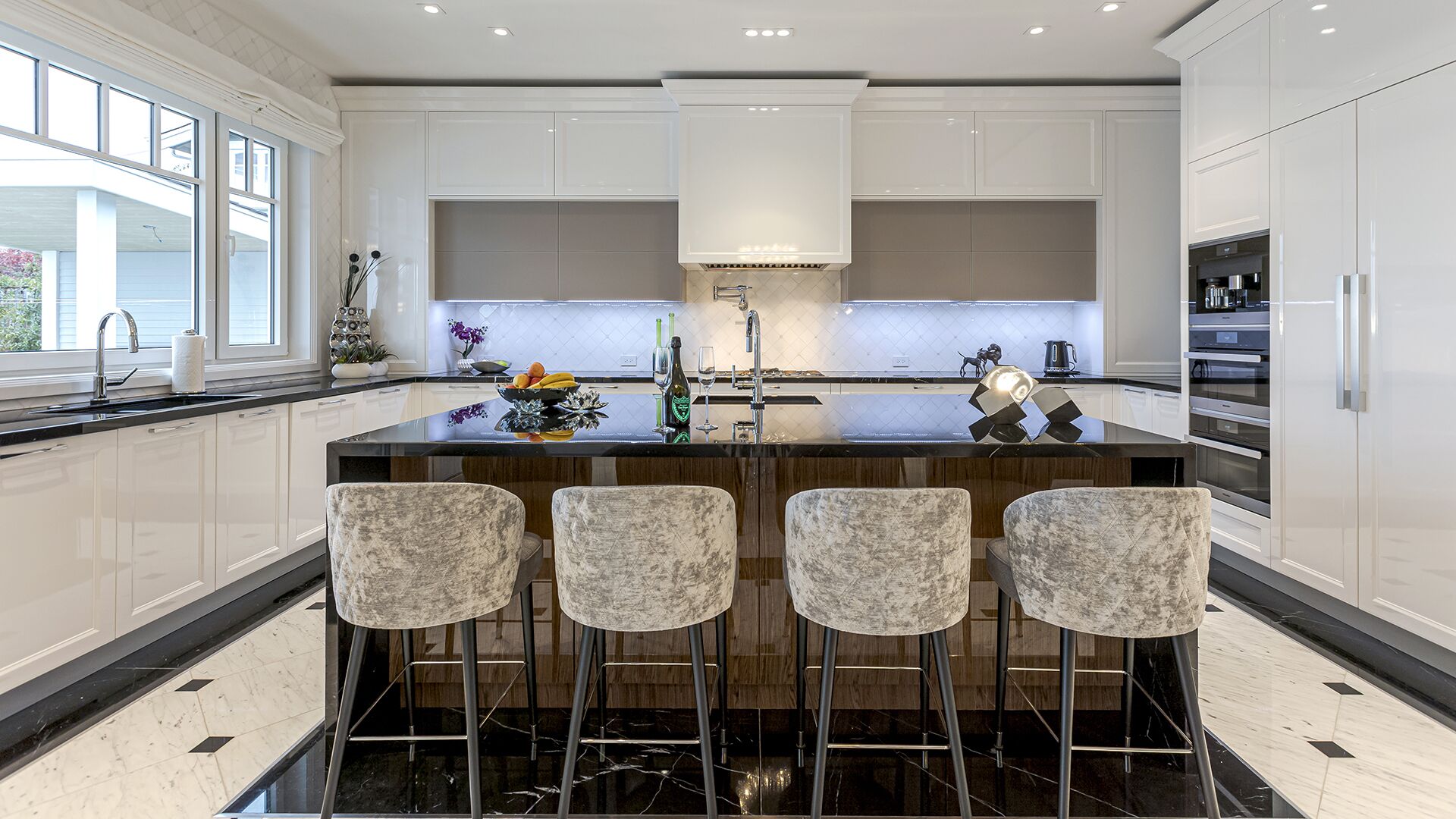 Kitchen island head-on view with premium appliances white lacquer cabinets and marble floors West Vancouver luxury home Eurohouse Construction