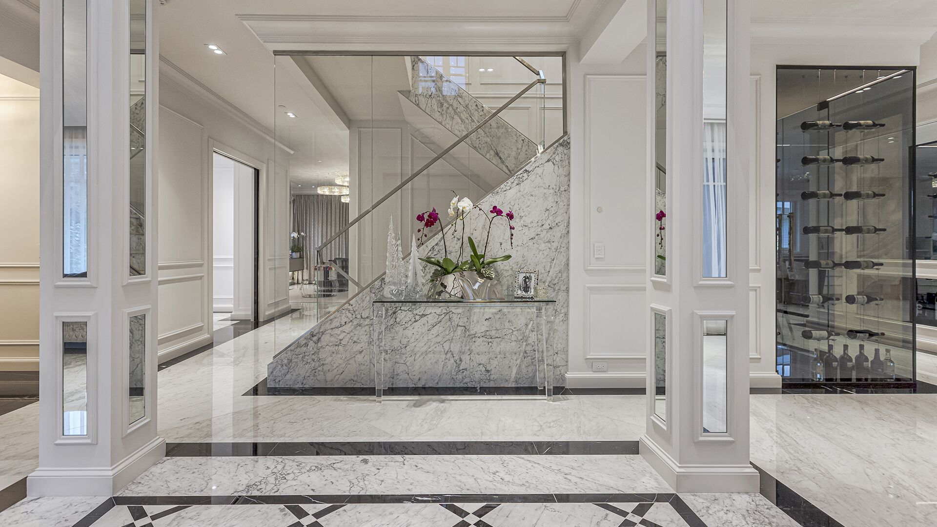 Grand marble foyer with glass staircase wine display tower and geometric marble floor West Vancouver luxury home by Eurohouse