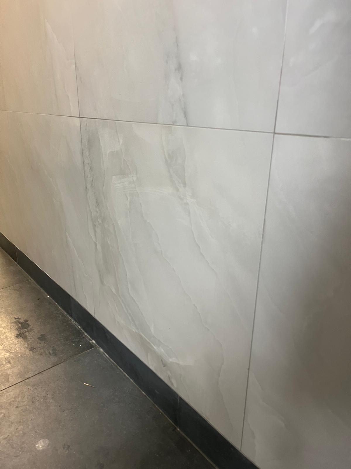 Completed wall tile installation with clean baseboard trim detail